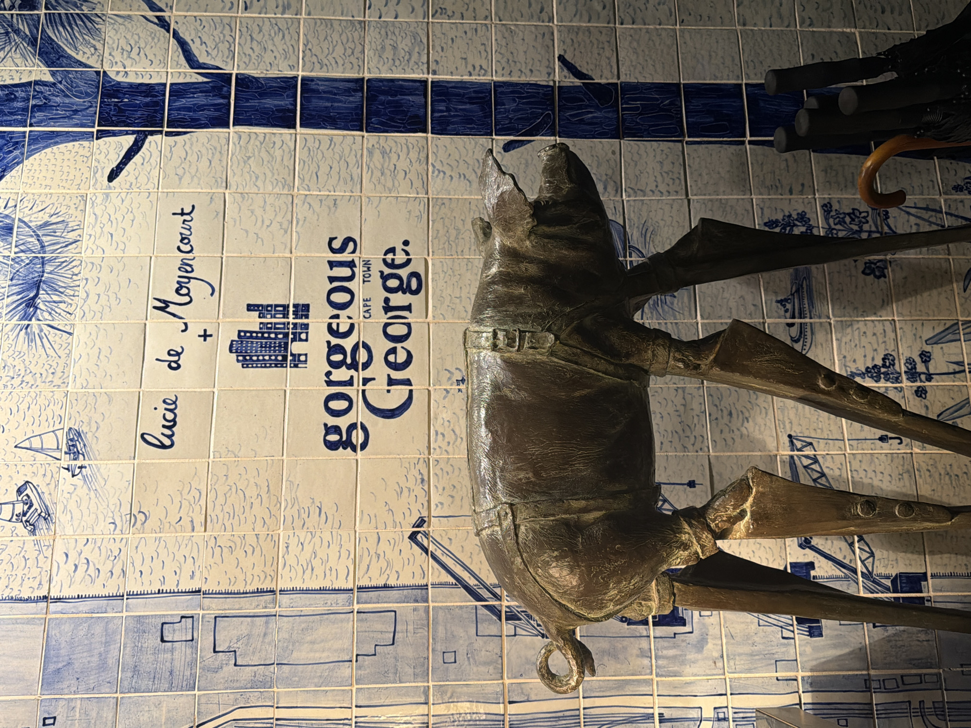 Bronze sculpture spotted against patterned tile wall in Cape Town