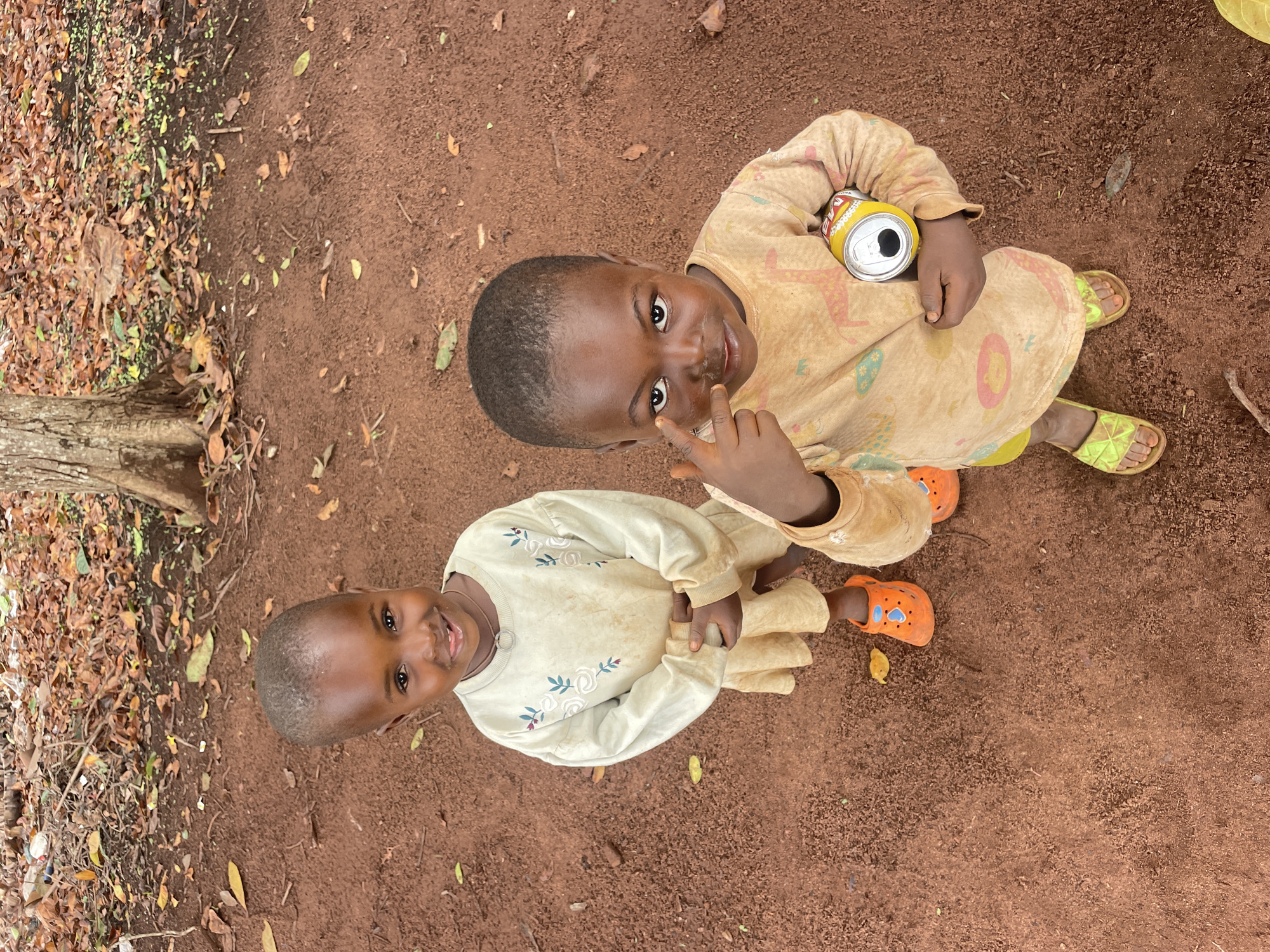 Children play and pose on red dirt in Ogbe, Nigeria