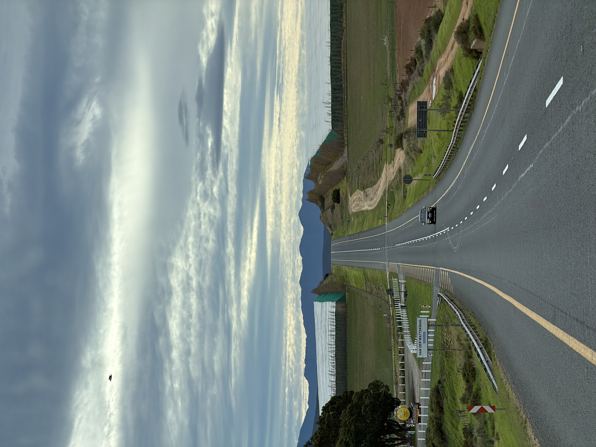 Car travels rural road through farmland in South Africa