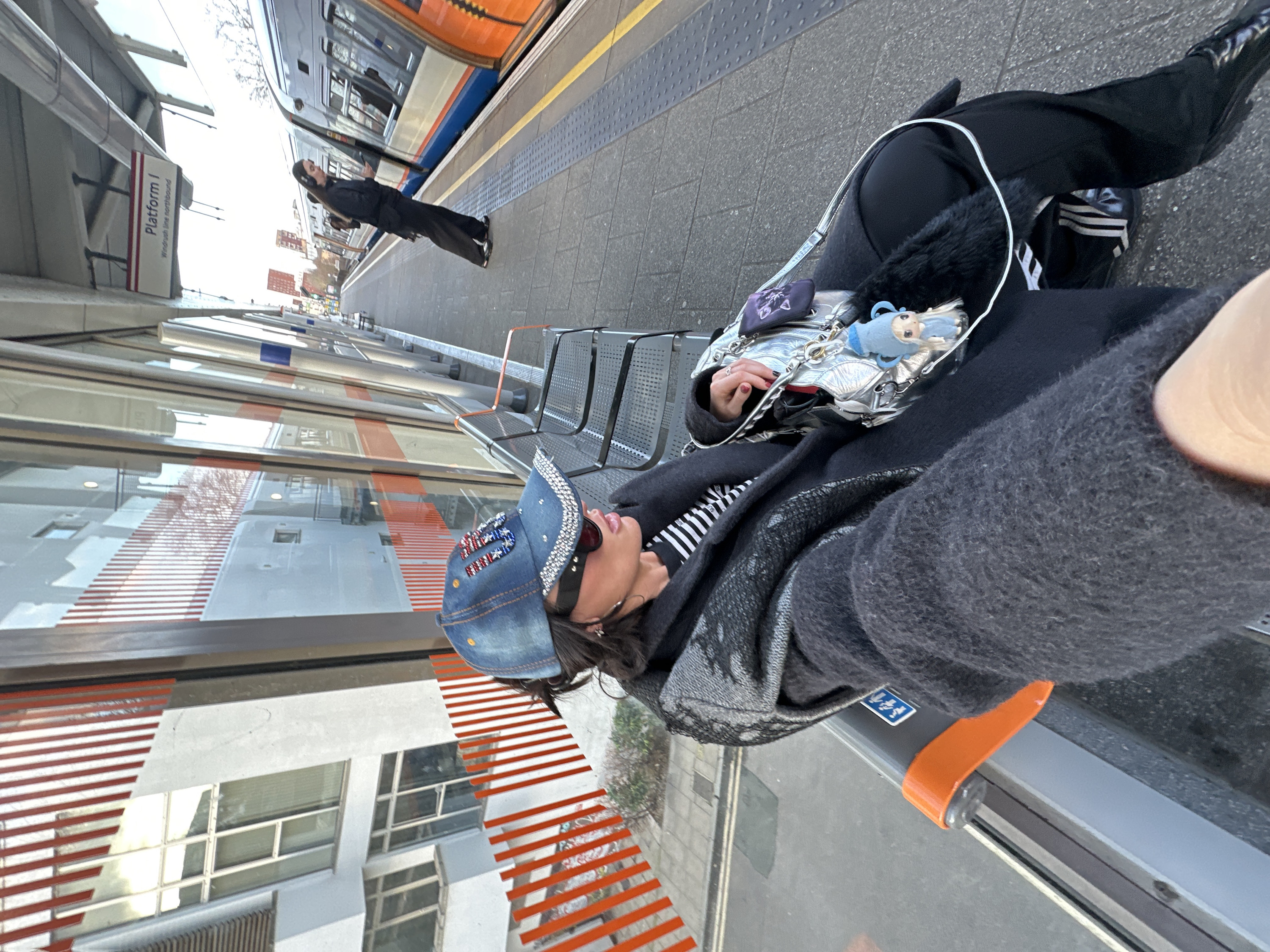 Person with silver handbag waits at London train platform