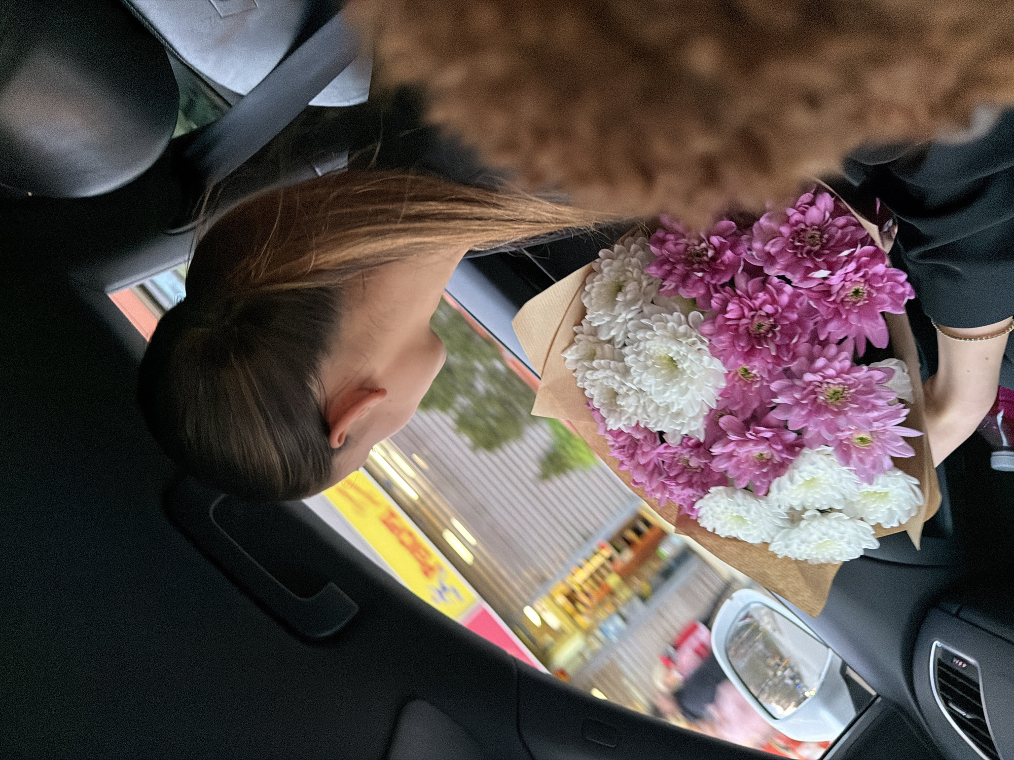 Woman carries flower bouquet in moving car in Sofia