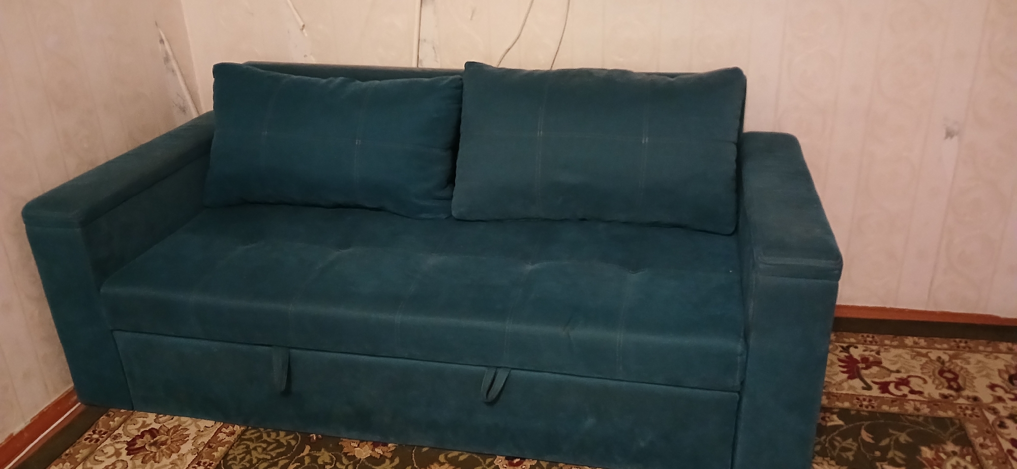 Teal sofa and a flexing pose inside a casual indoor space