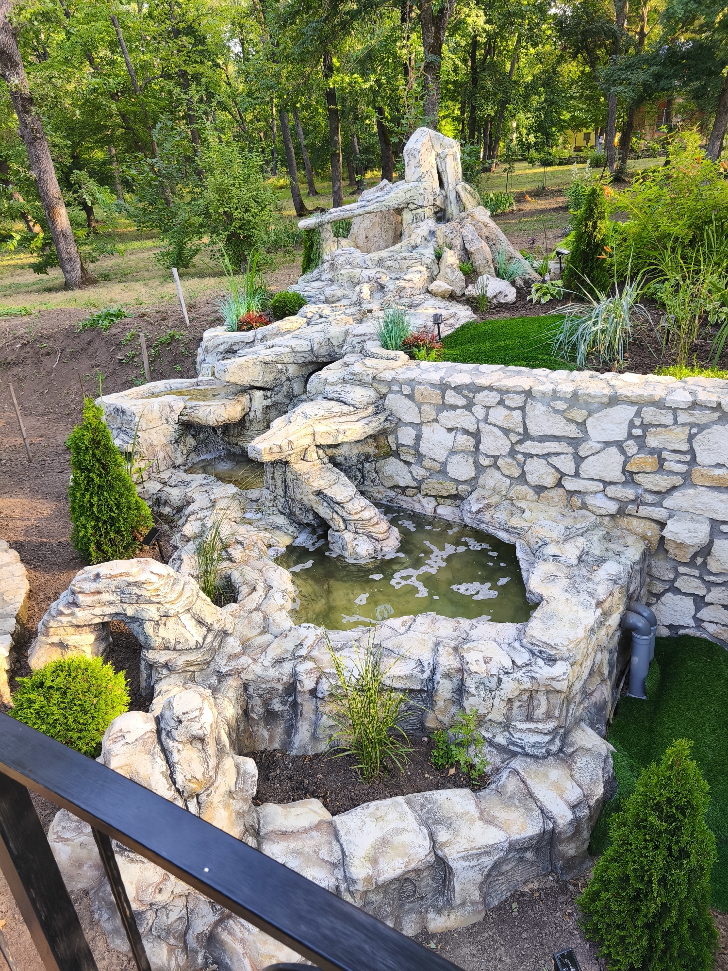Ornamental garden with rock waterfall and evergreens in Stroiesti