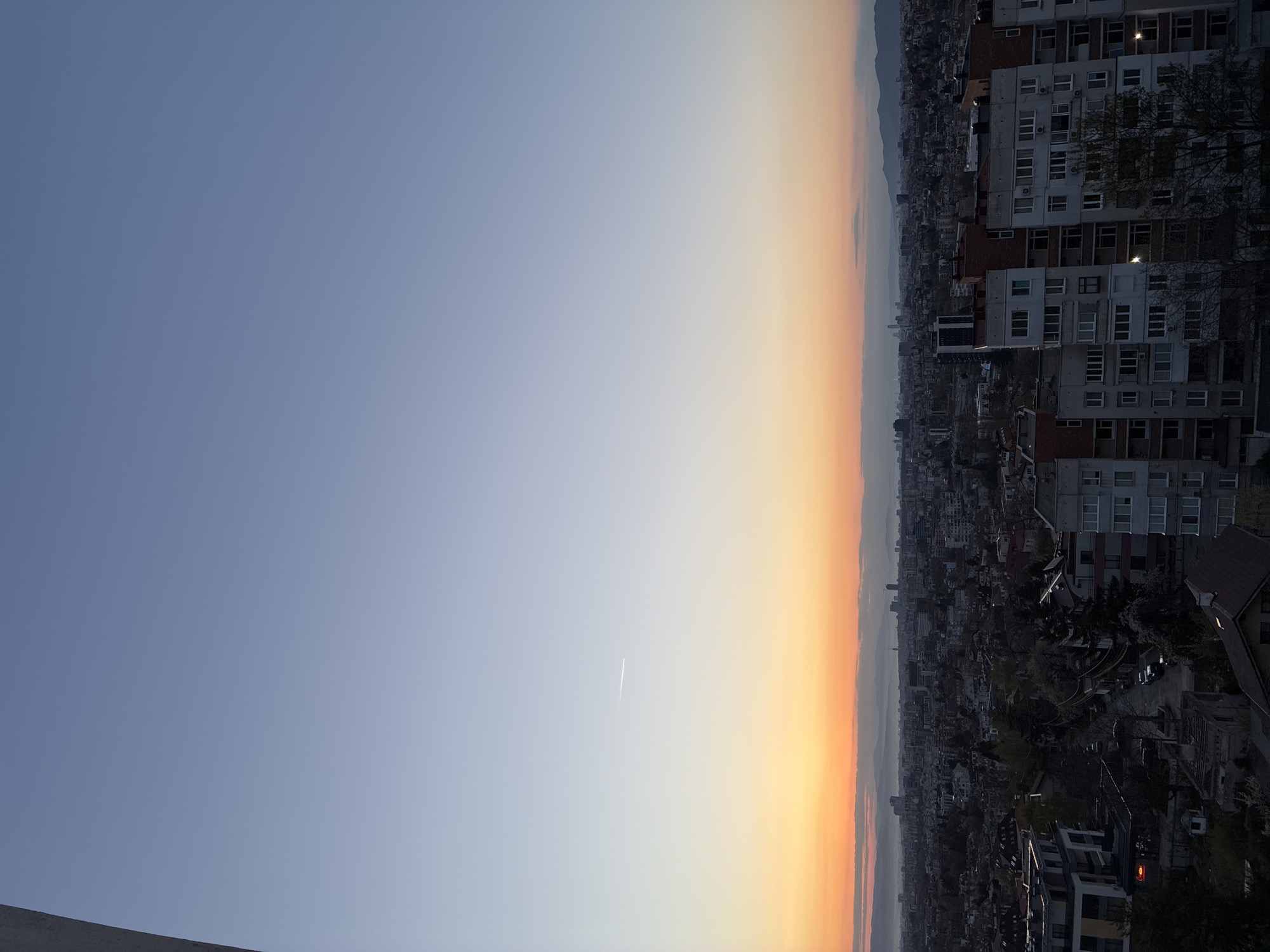 Dawn sky with contrail observed over Sofia residential district