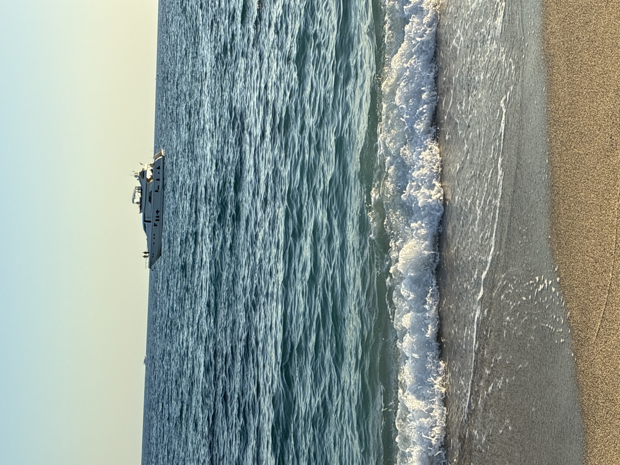 Alanya coastline at golden hour — beach, waves, and a yacht