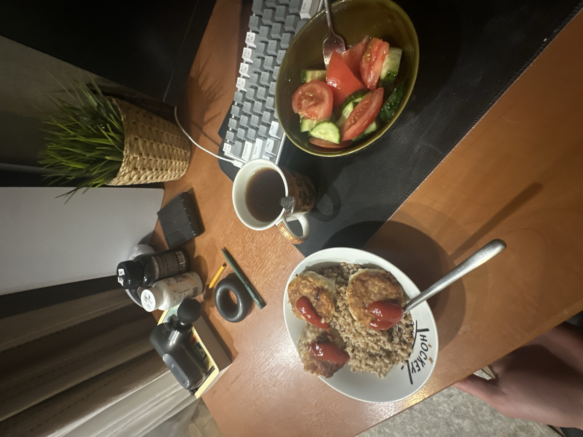 Young man working at cluttered desk with salad lunch