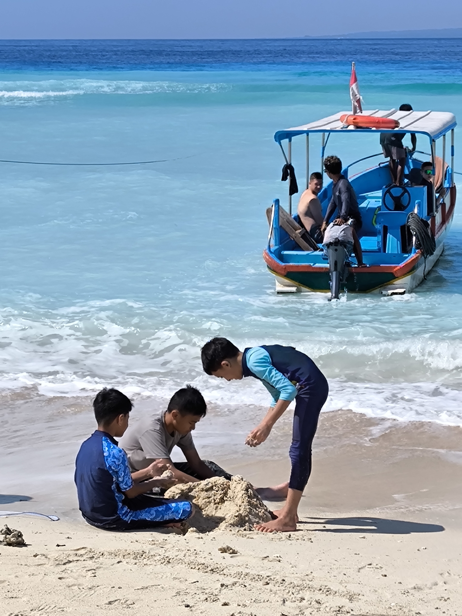 Lazy morning on an Indonesian beach with boats, kids, and food