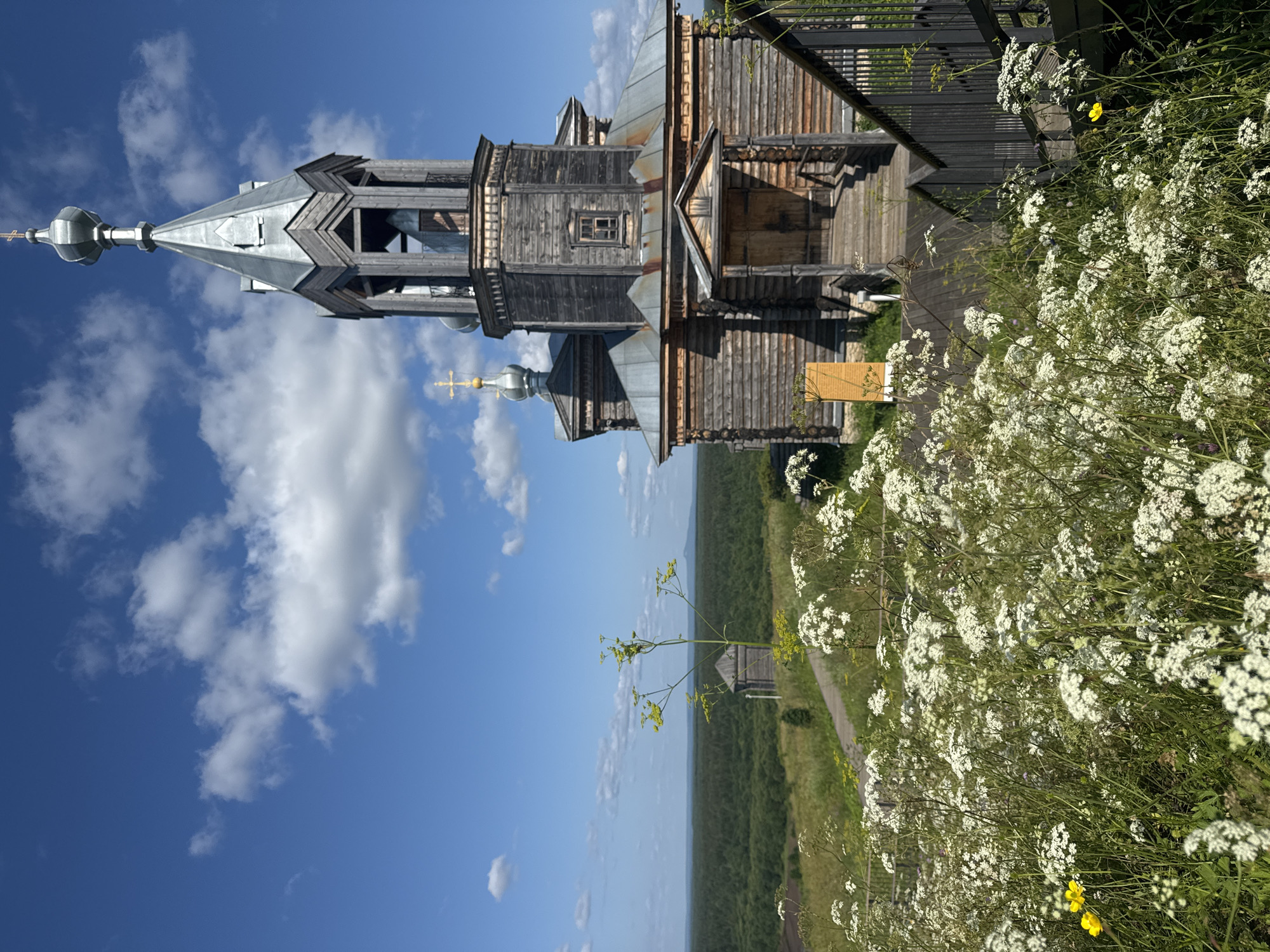 Wooden church and daisies on stairs in Cherdyn, Russia