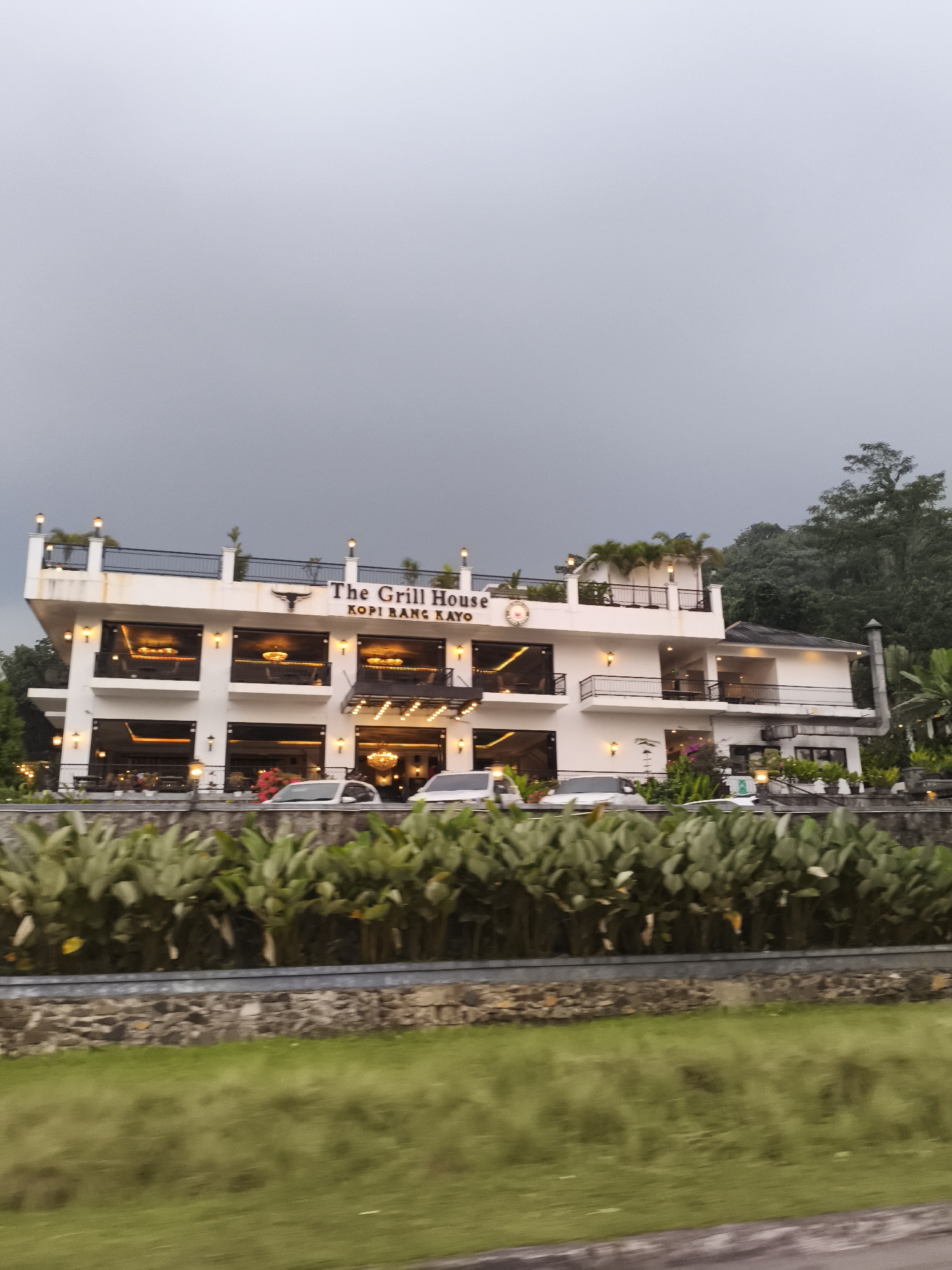 Morning traffic flows past cafes on tree-lined Babakan Madang road