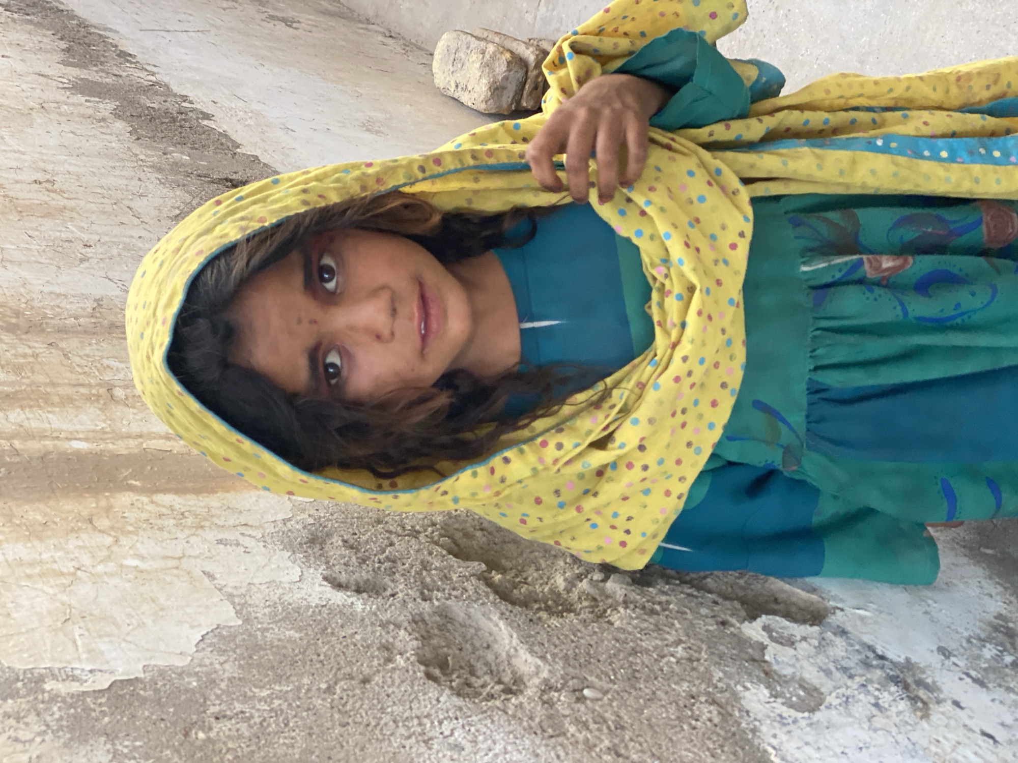 Teal dress against a weathered wall in Kandahar