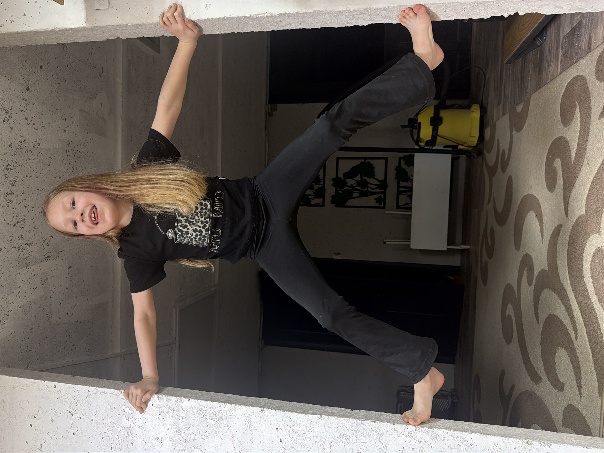 Girl playfully hangs upside down in building opening, Chaikovsky