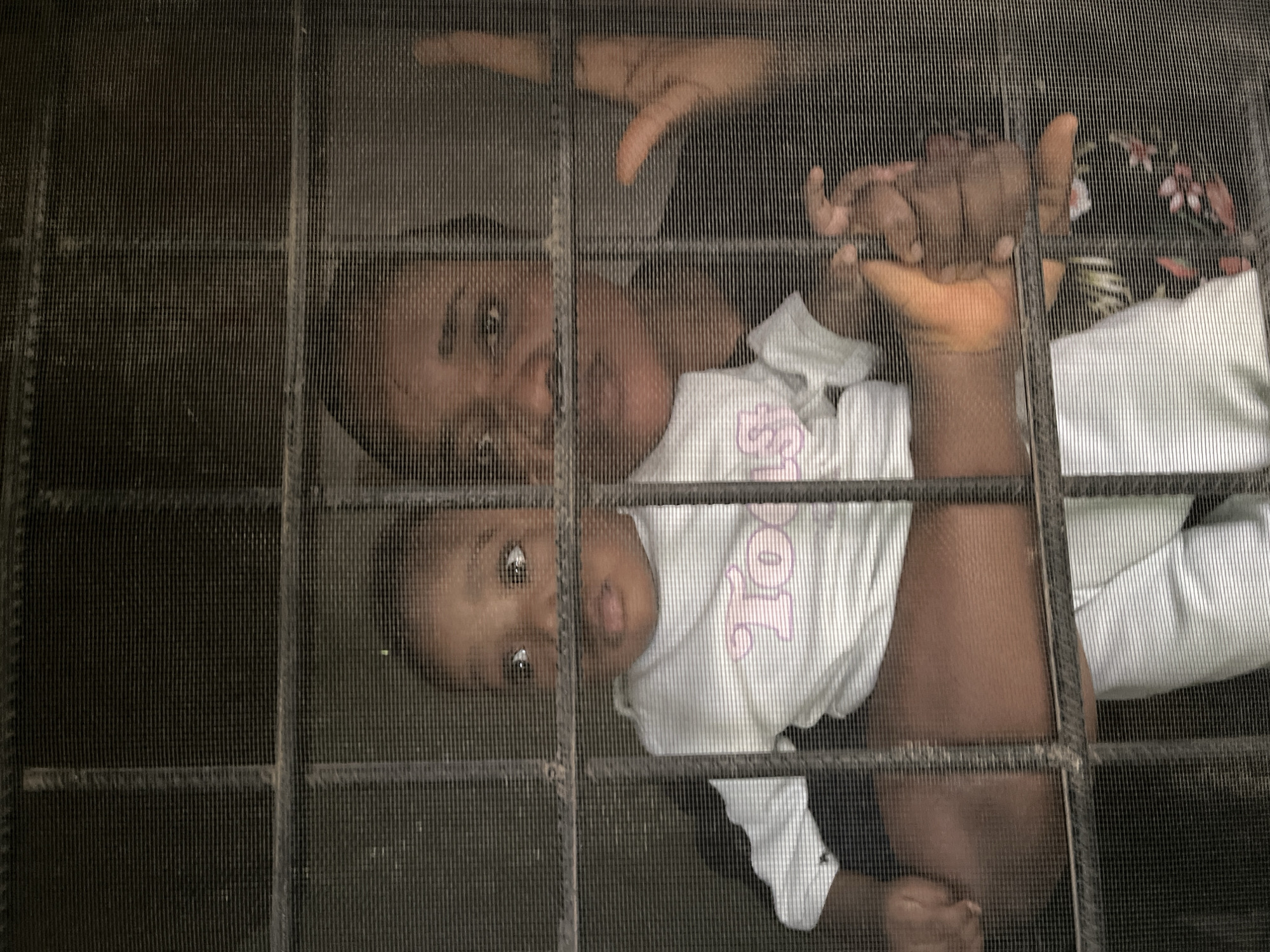 Two faces at a wire mesh window in Barakin Akawo, Nigeria