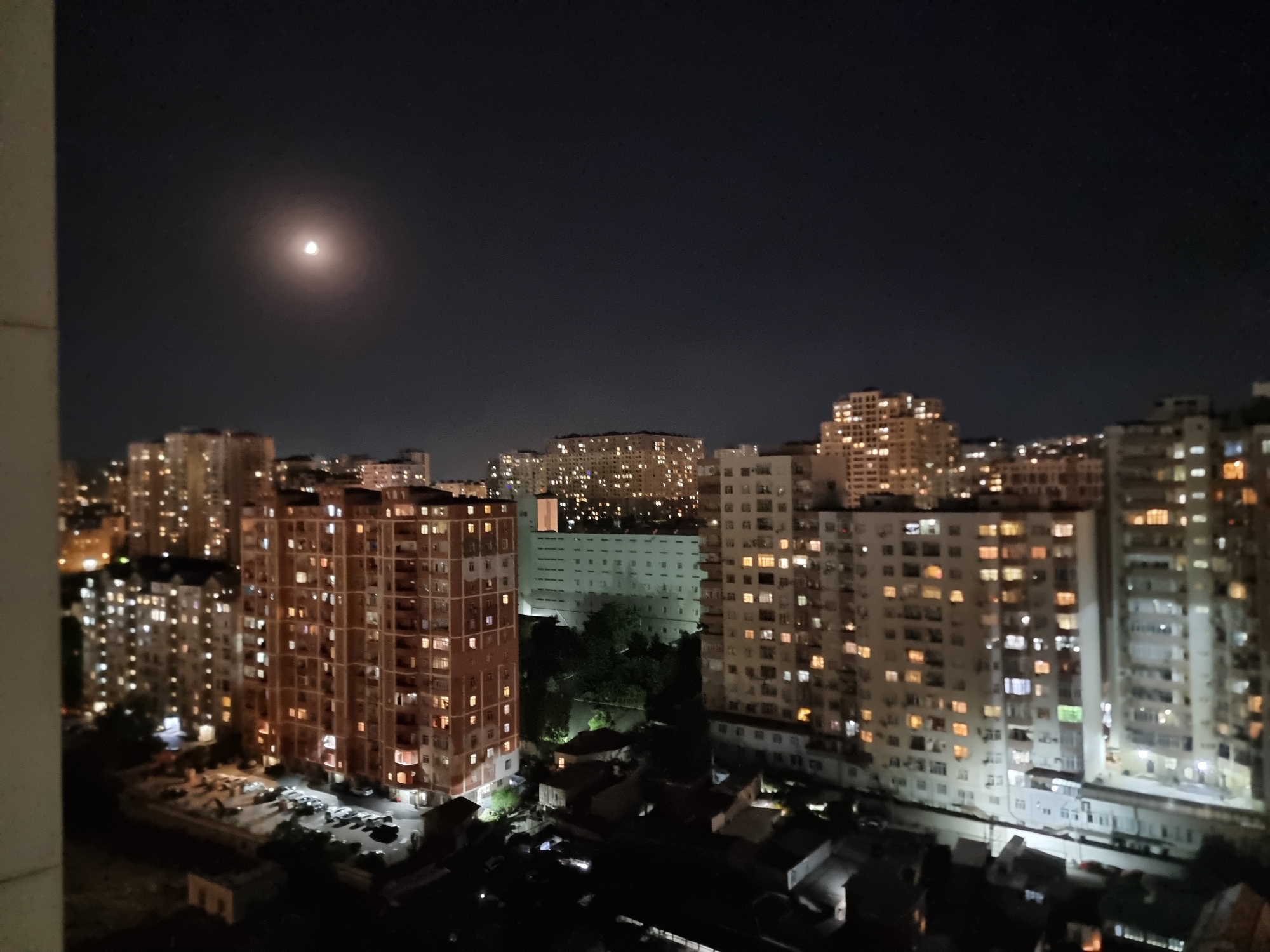 City at night, moon out, rooftop perspective