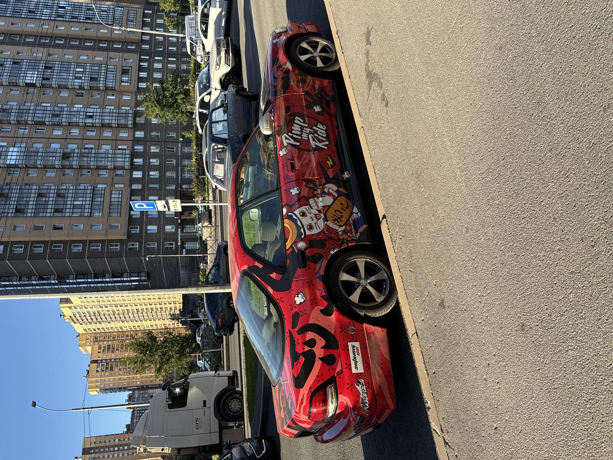 Anime-wrapped red sedan parked on a Pargolovo residential street