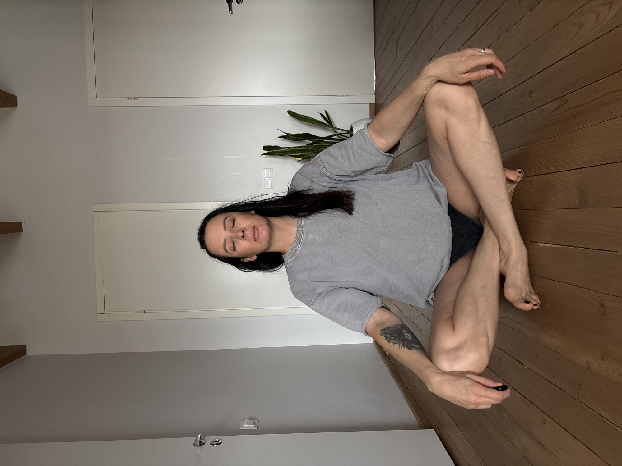 Woman sits cross-legged indoors in Chaikovsky, Russia