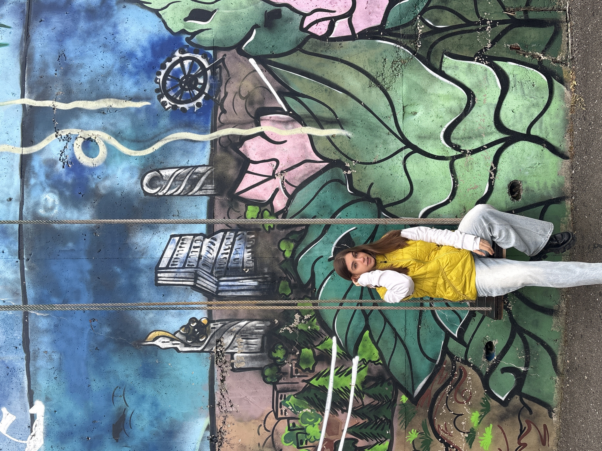 Woman poses against graffiti mural in Mnatobi, Georgia