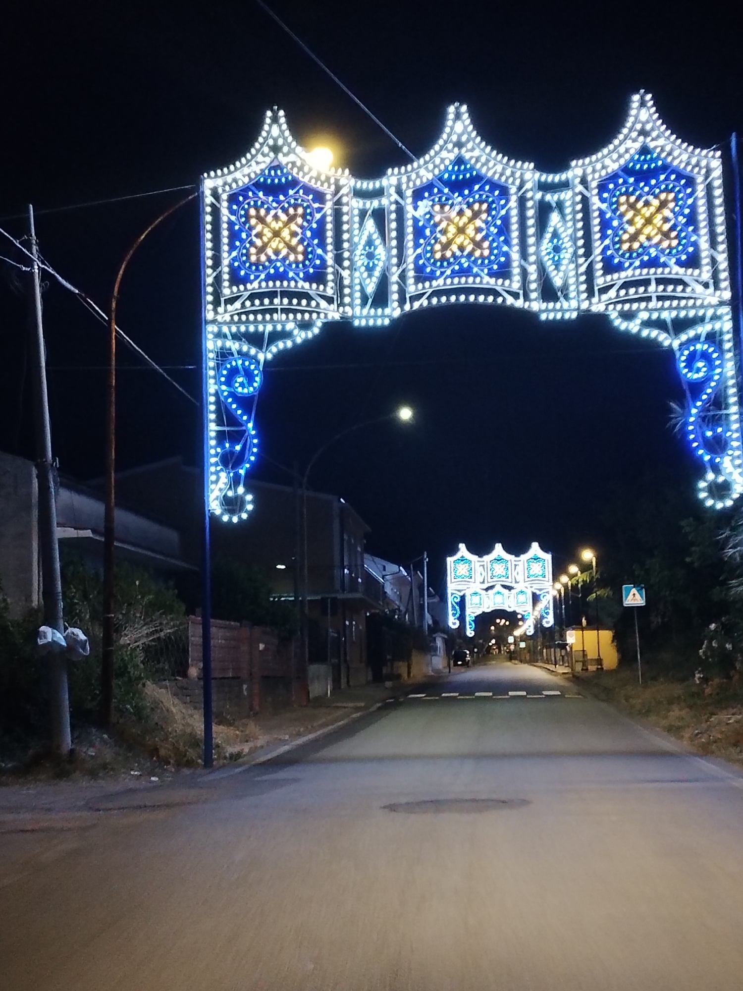Ornate archway illuminates street scene in Sessa Aurunca, Italy
