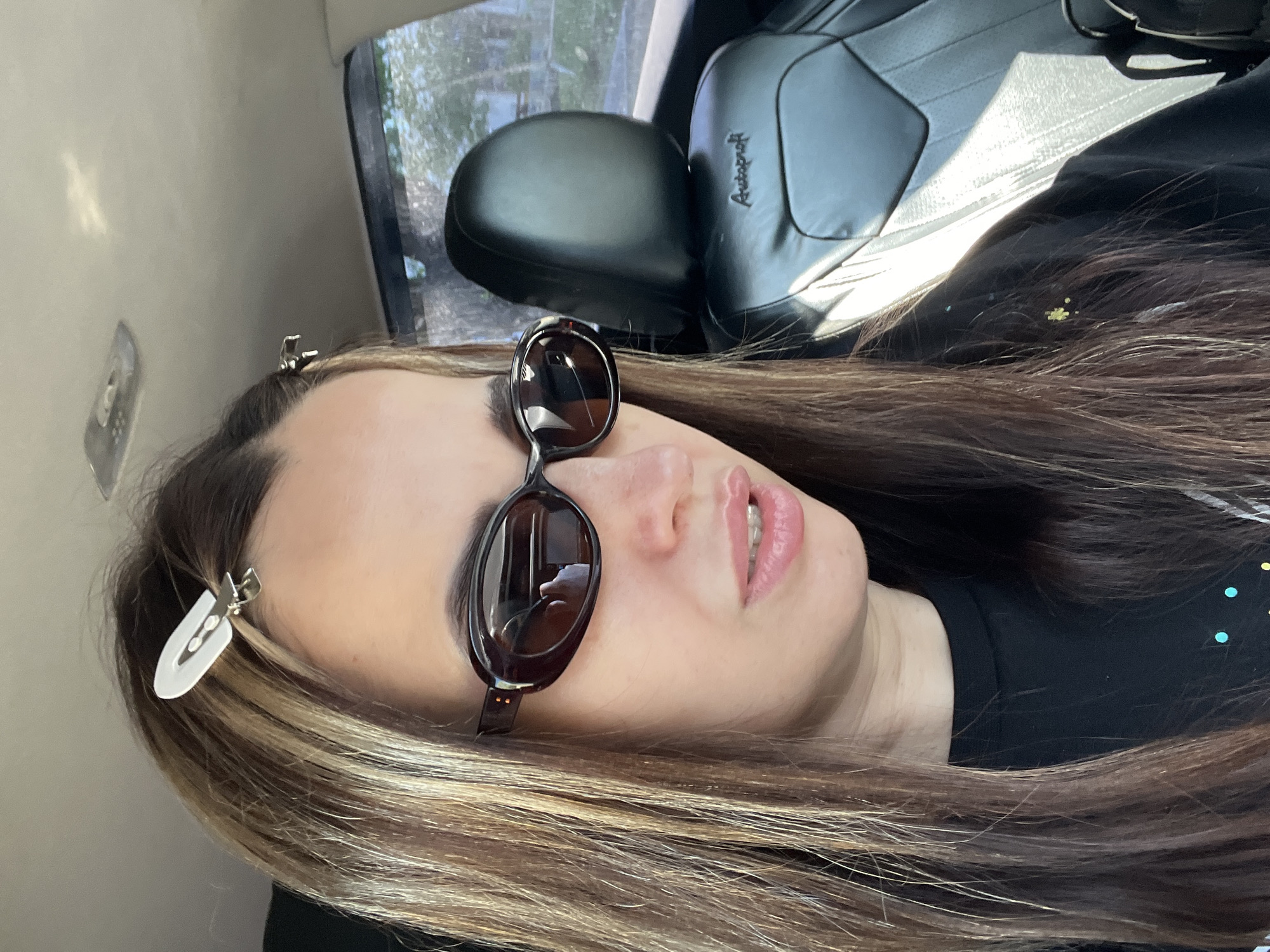 Woman takes car selfies wearing sunglasses and black shirt