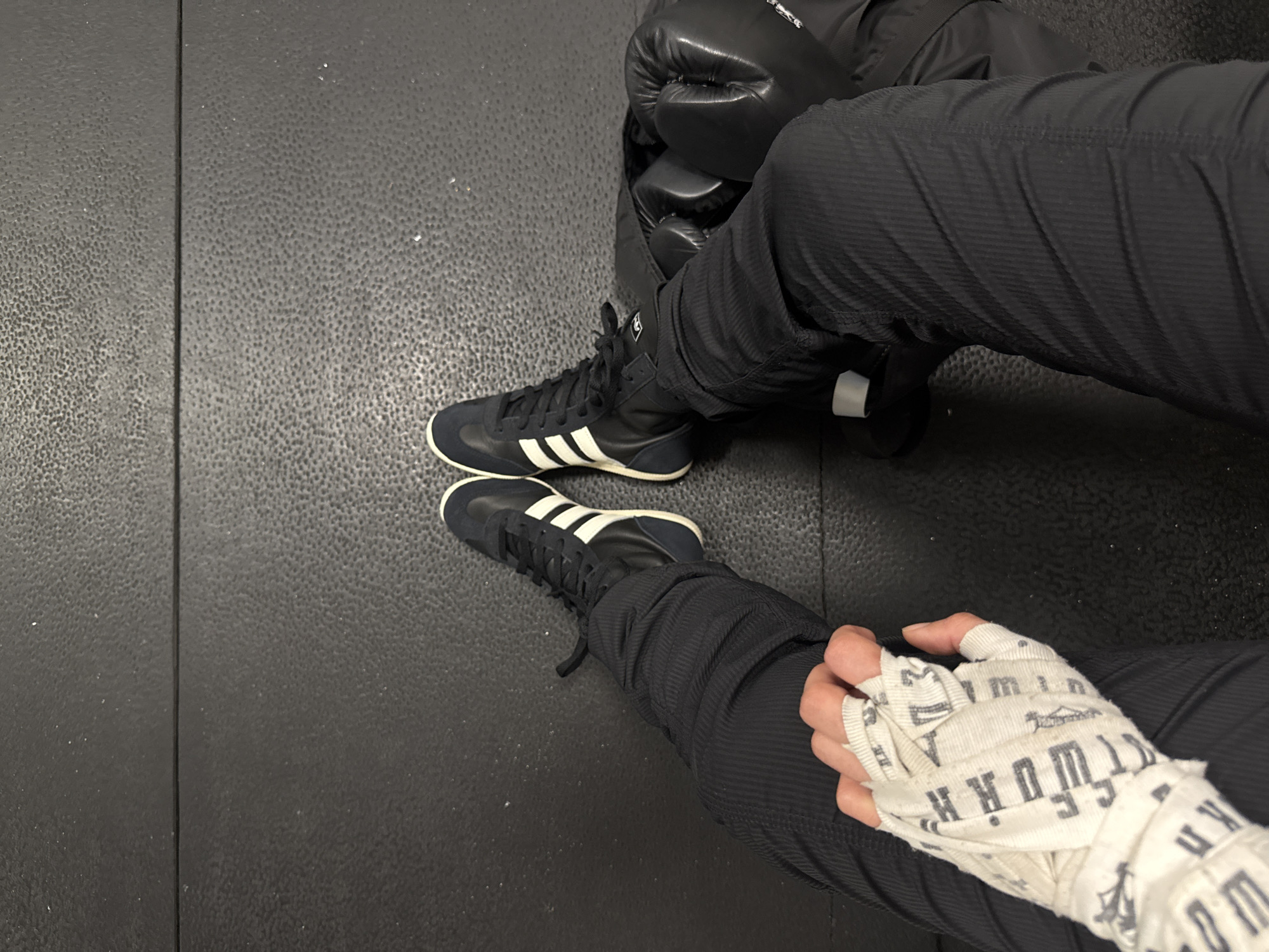 Person in Adidas shoes sits on gym mat in London