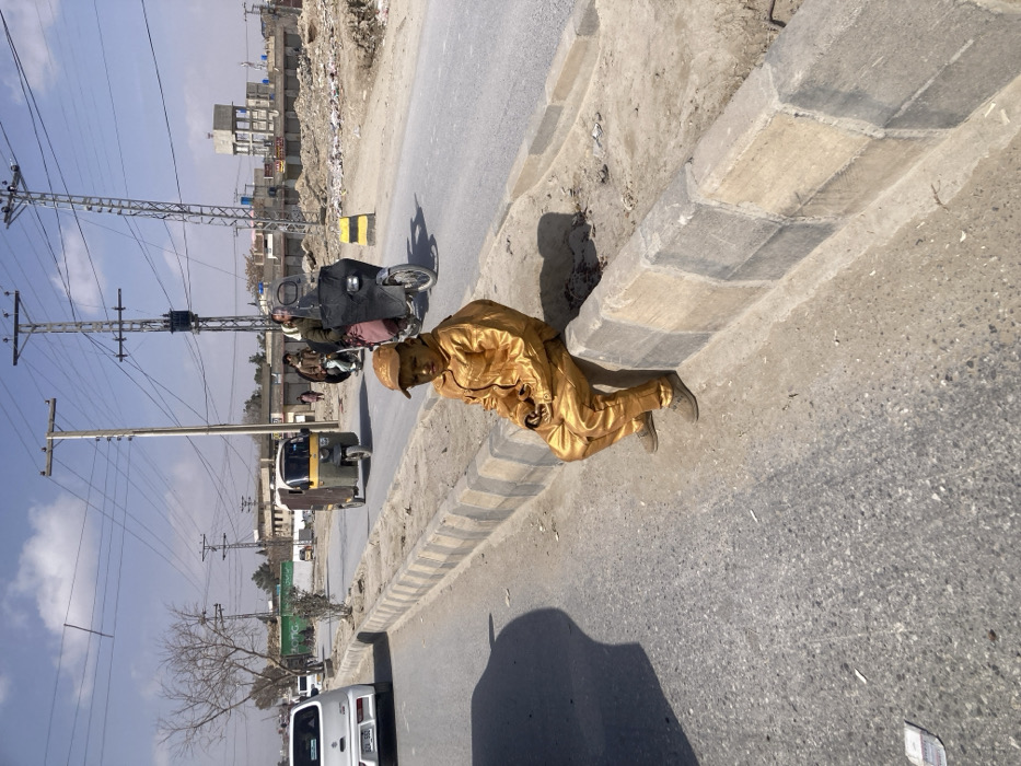 Man in gold suit sits roadside in Quetta