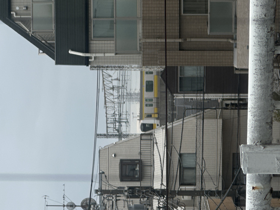 Yellow train spotted between buildings in Suginami district