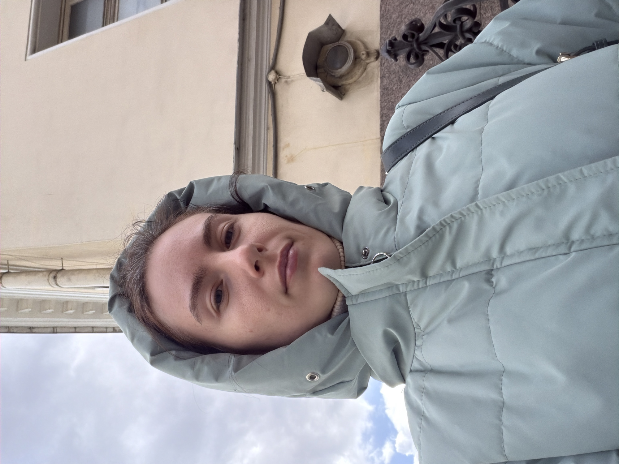 Woman photographed on overcast Saint Petersburg street amid traditional architecture