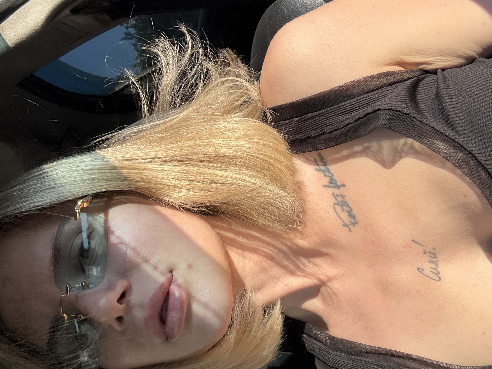 Tattooed blonde woman photographed in car, indoors in Mayma