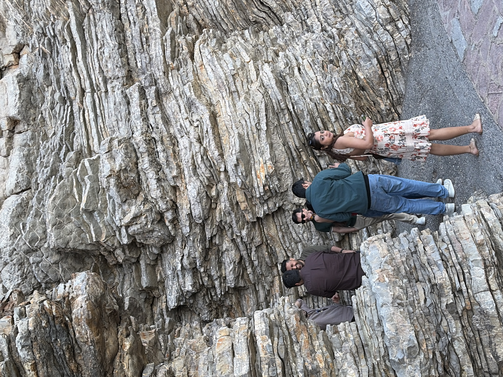 Tourists pose at scenic Budva cliff formation during sunset