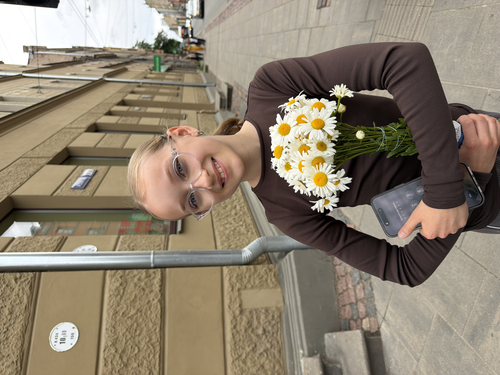 Girl with daisy bouquet photographed on Riga sidewalk