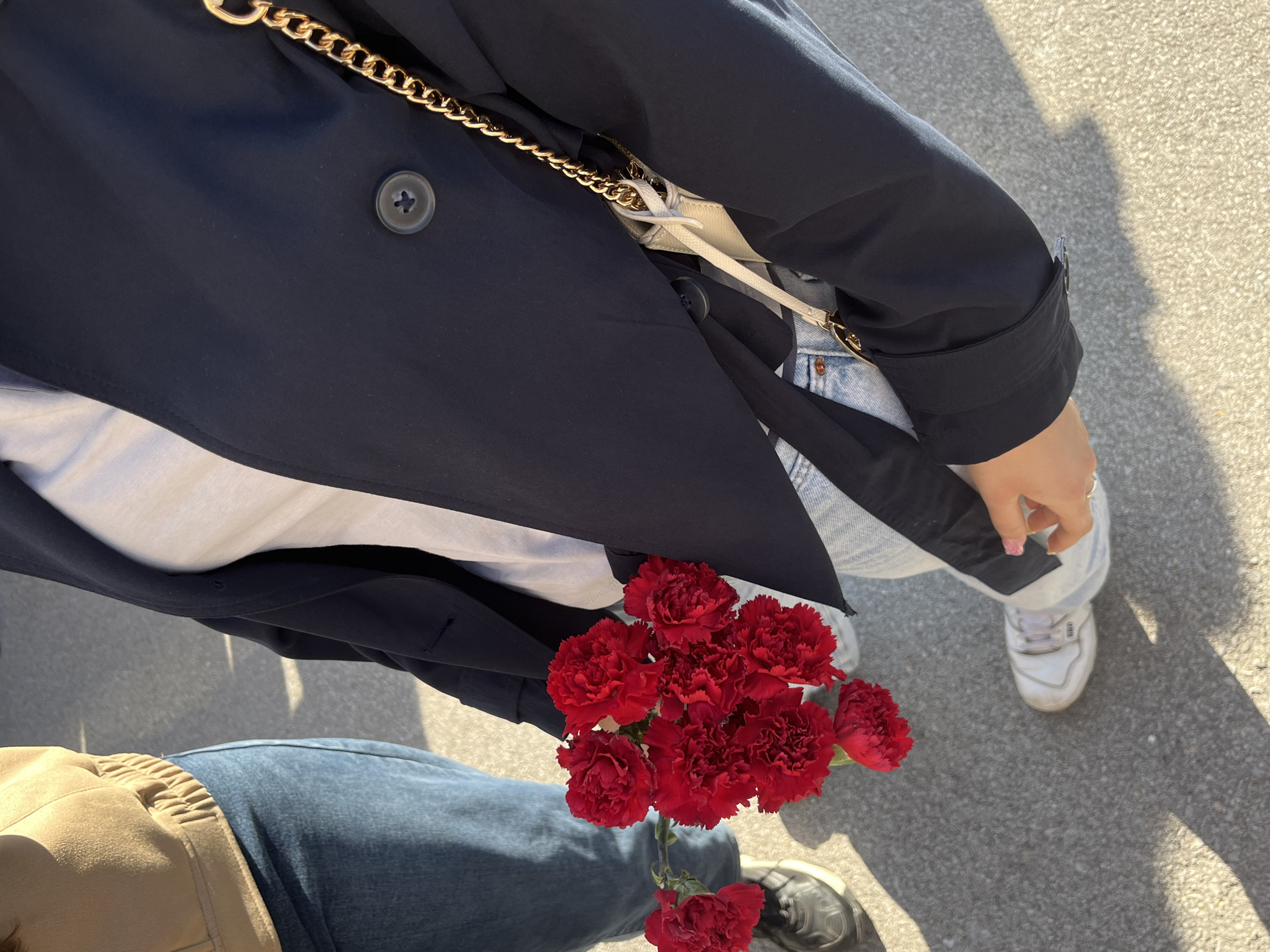 Two people hold red carnations on Ruse sidewalk