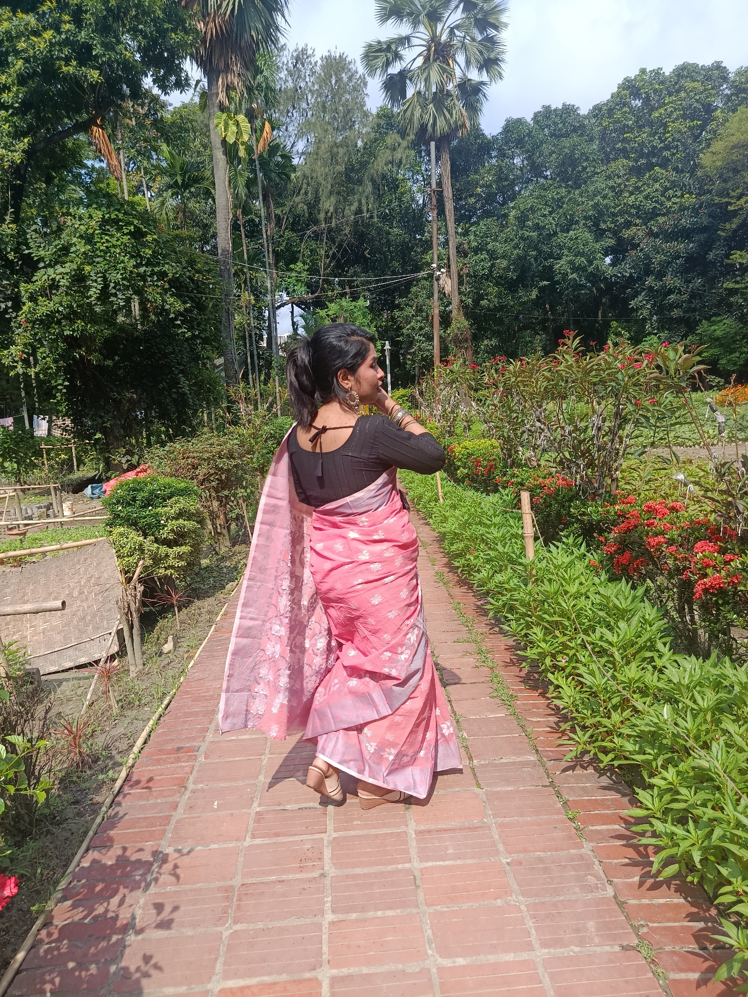 Woman in pink sari visits horticultural office garden in Dhaka