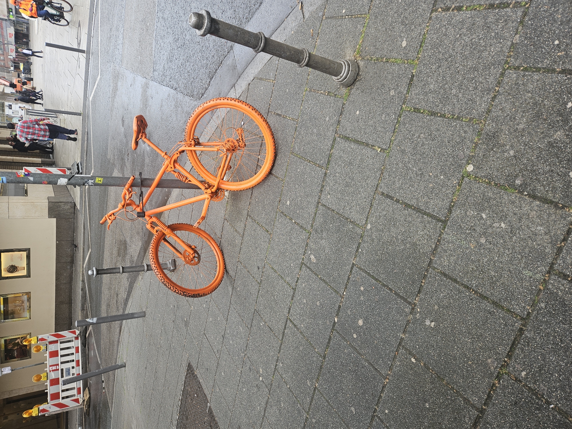 Orange bicycle spotted locked to bollard in Frankfurt