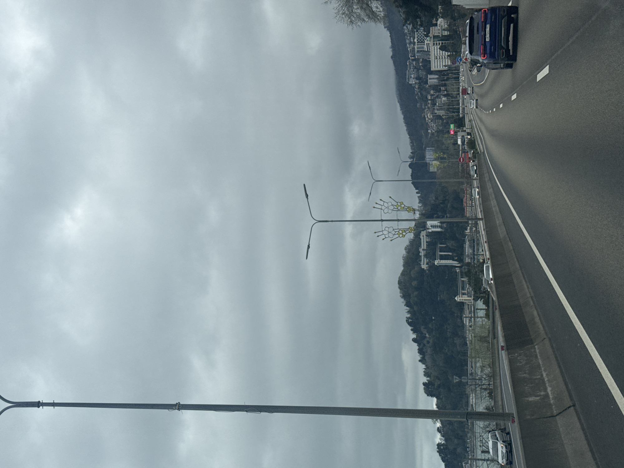 Blue car travels Sochi highway amid cloudy morning traffic