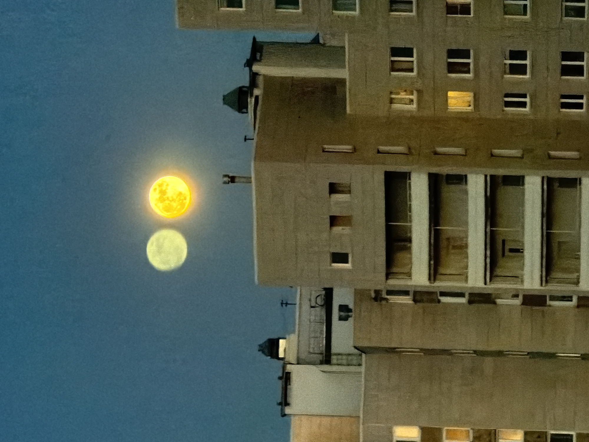 Moon rises beside residential building in Murino, Russia
