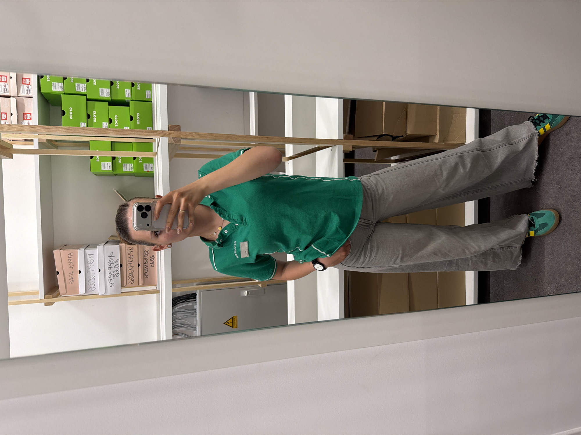 Person takes mirror selfie in shoe storage room