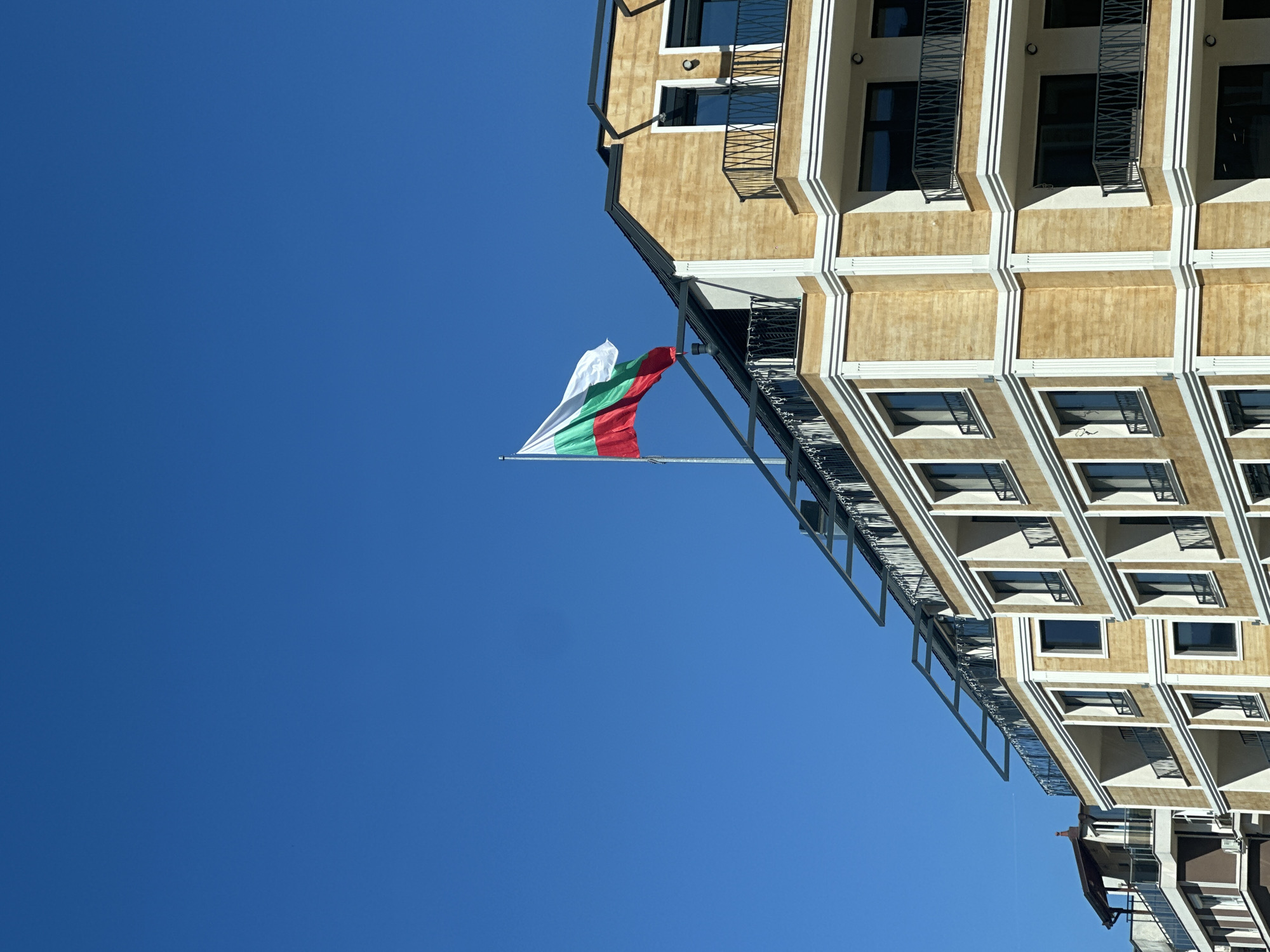 Bulgarian flag flies over Sofia building under clear skies