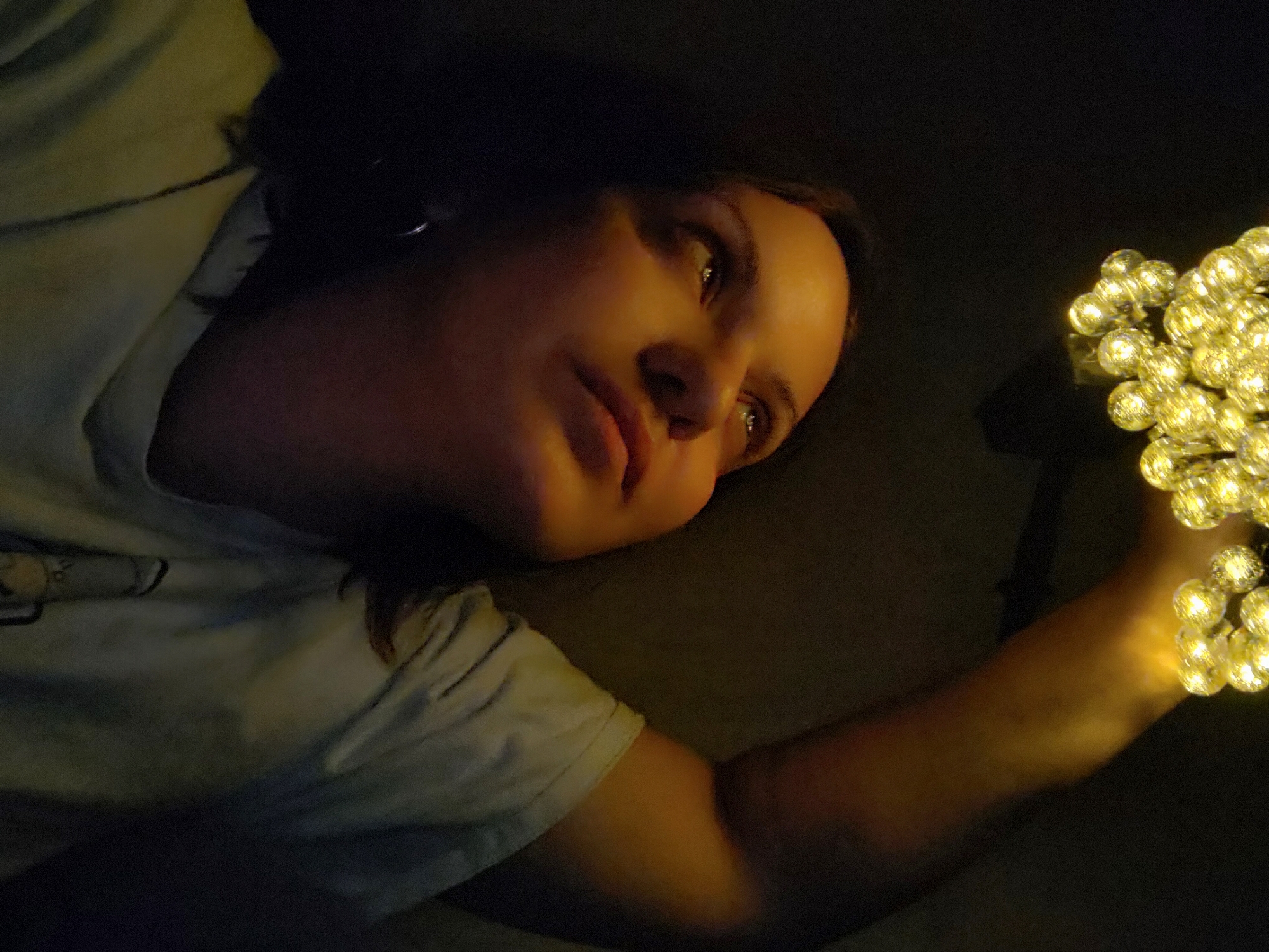 Woman holds fairy lights in dimly lit indoor space