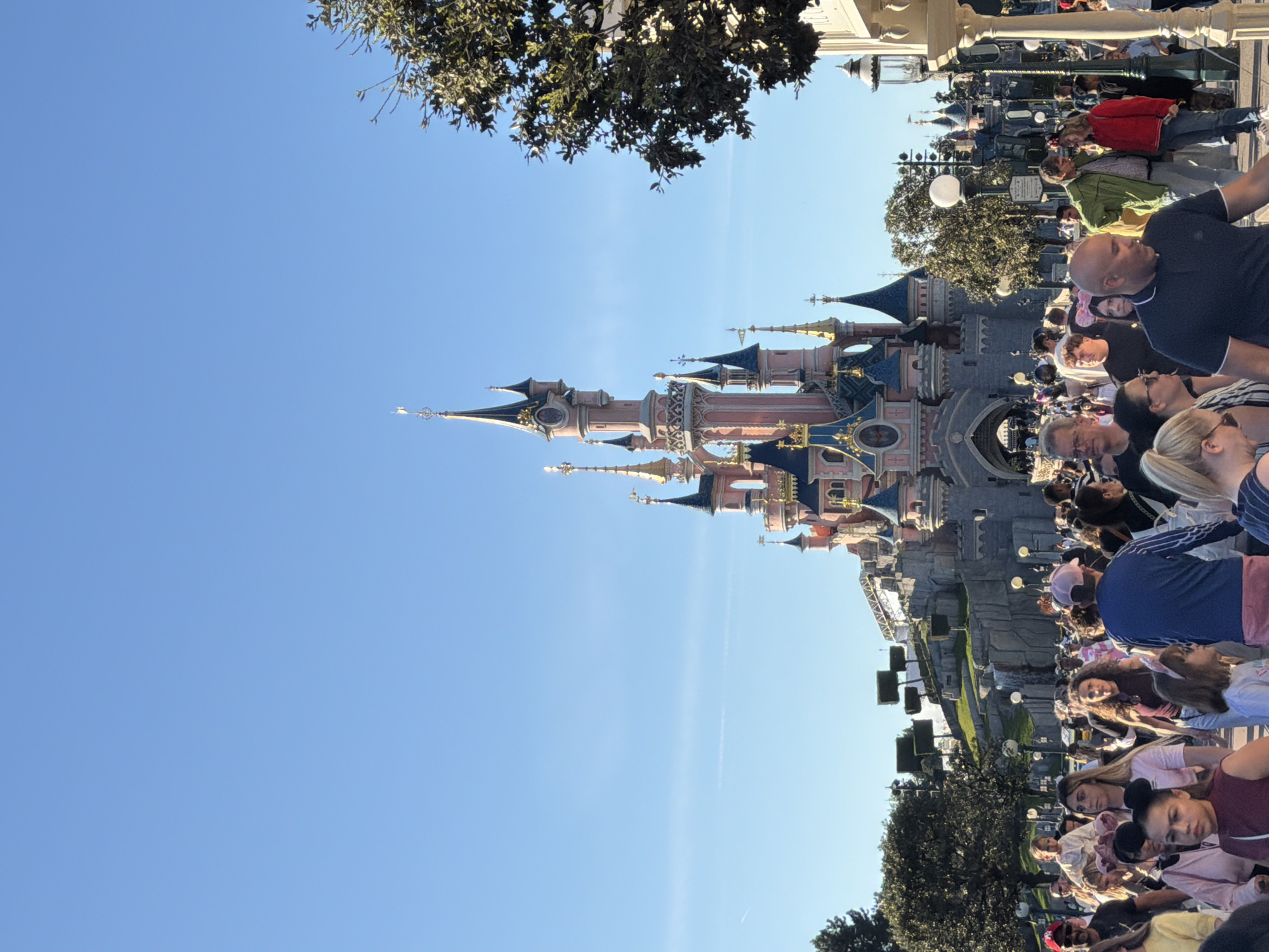 Crowds gather at Disneyland Paris castle under clear skies