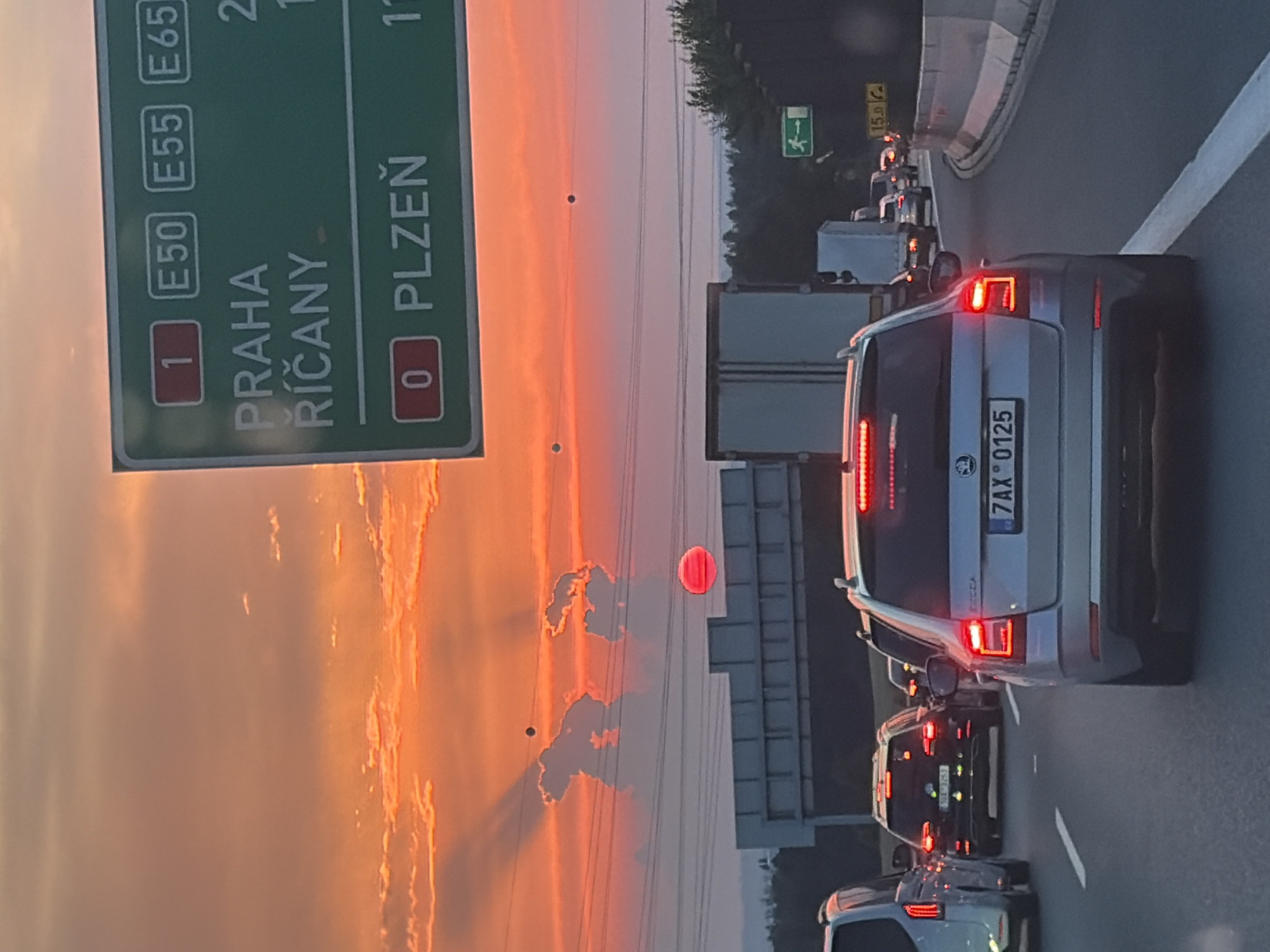 Rush hour traffic rolls through suburban Prague under a sunset sky