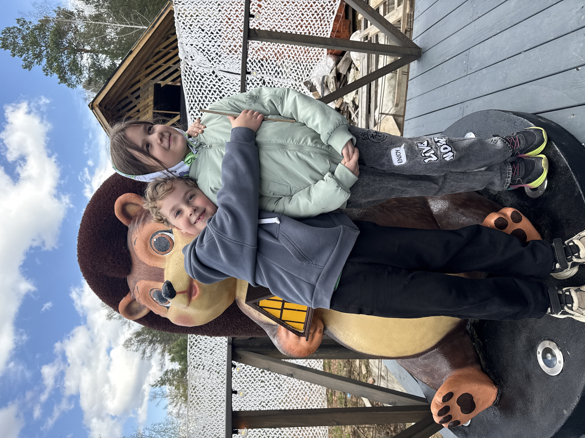Children play on bear statue near A-frame cabin in Divnogorsk