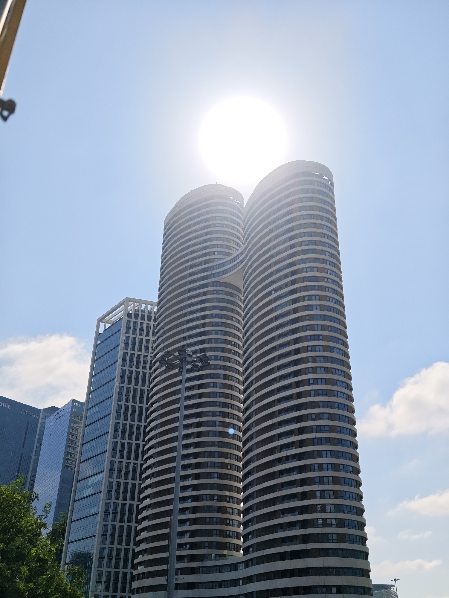 Sun and sky peek around a curved Tel Aviv building