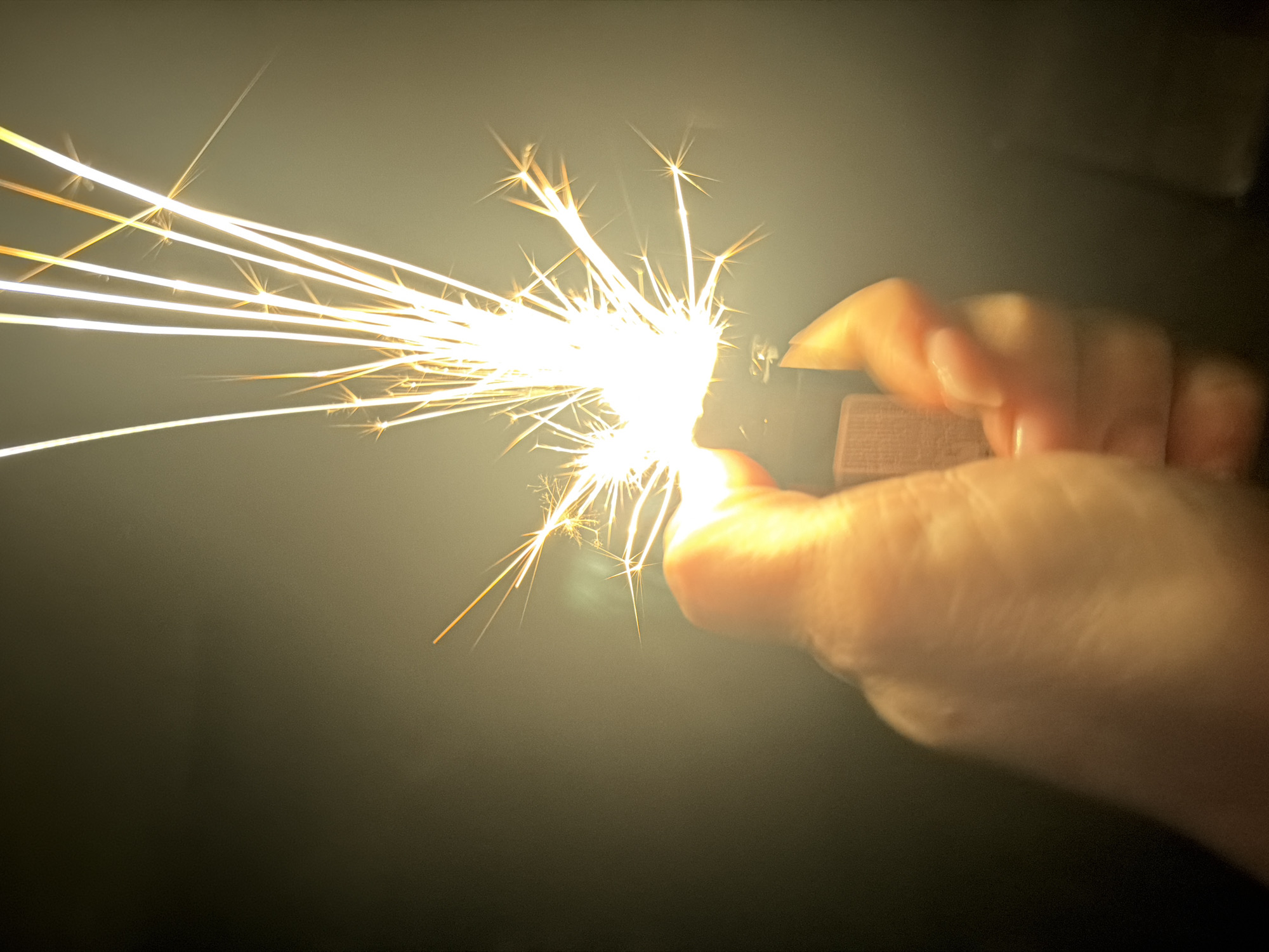 Hand holds sparking lighter in dark setting