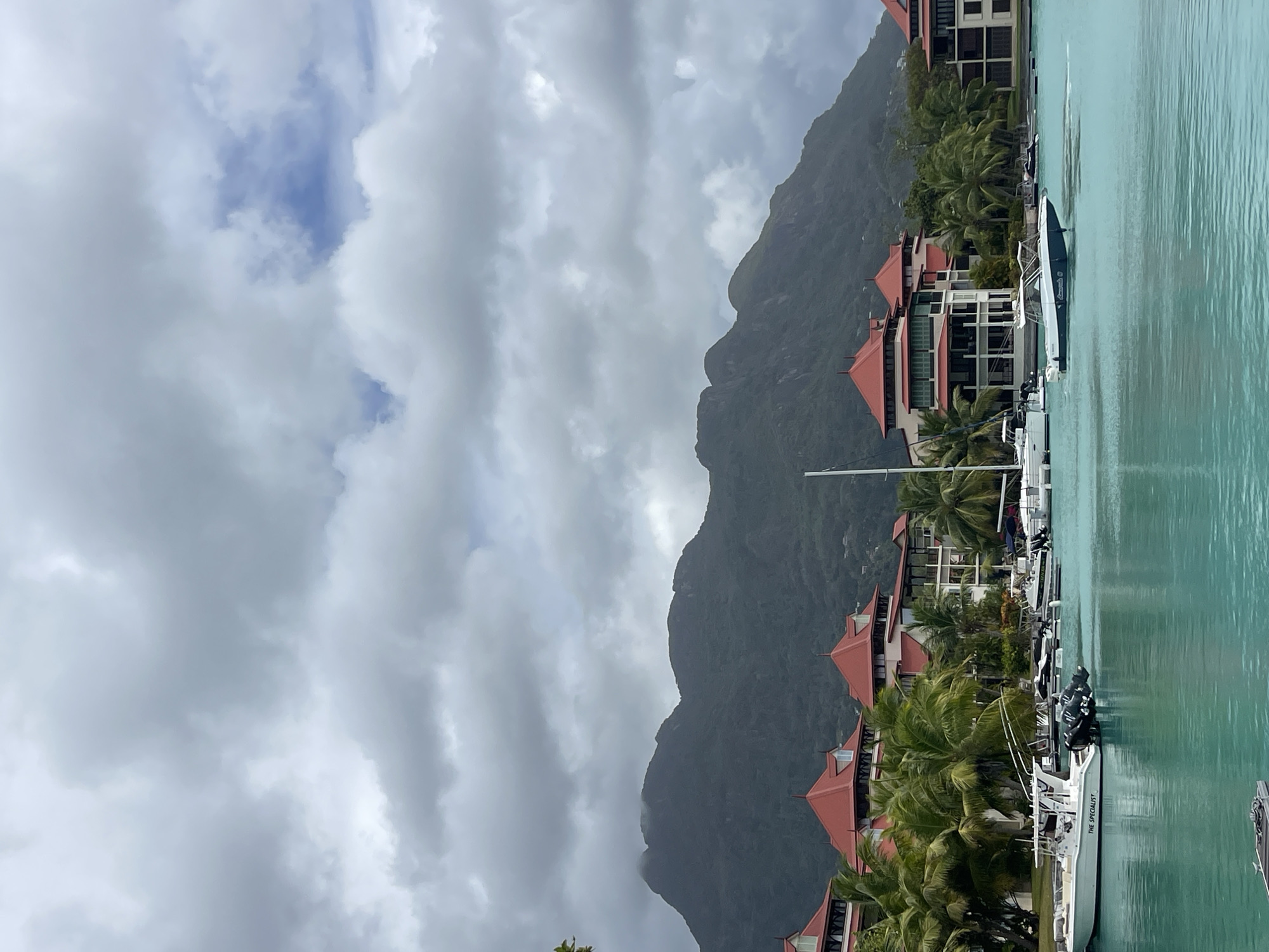 Calm Seychelles bay with red-roofed buildings and moored boats