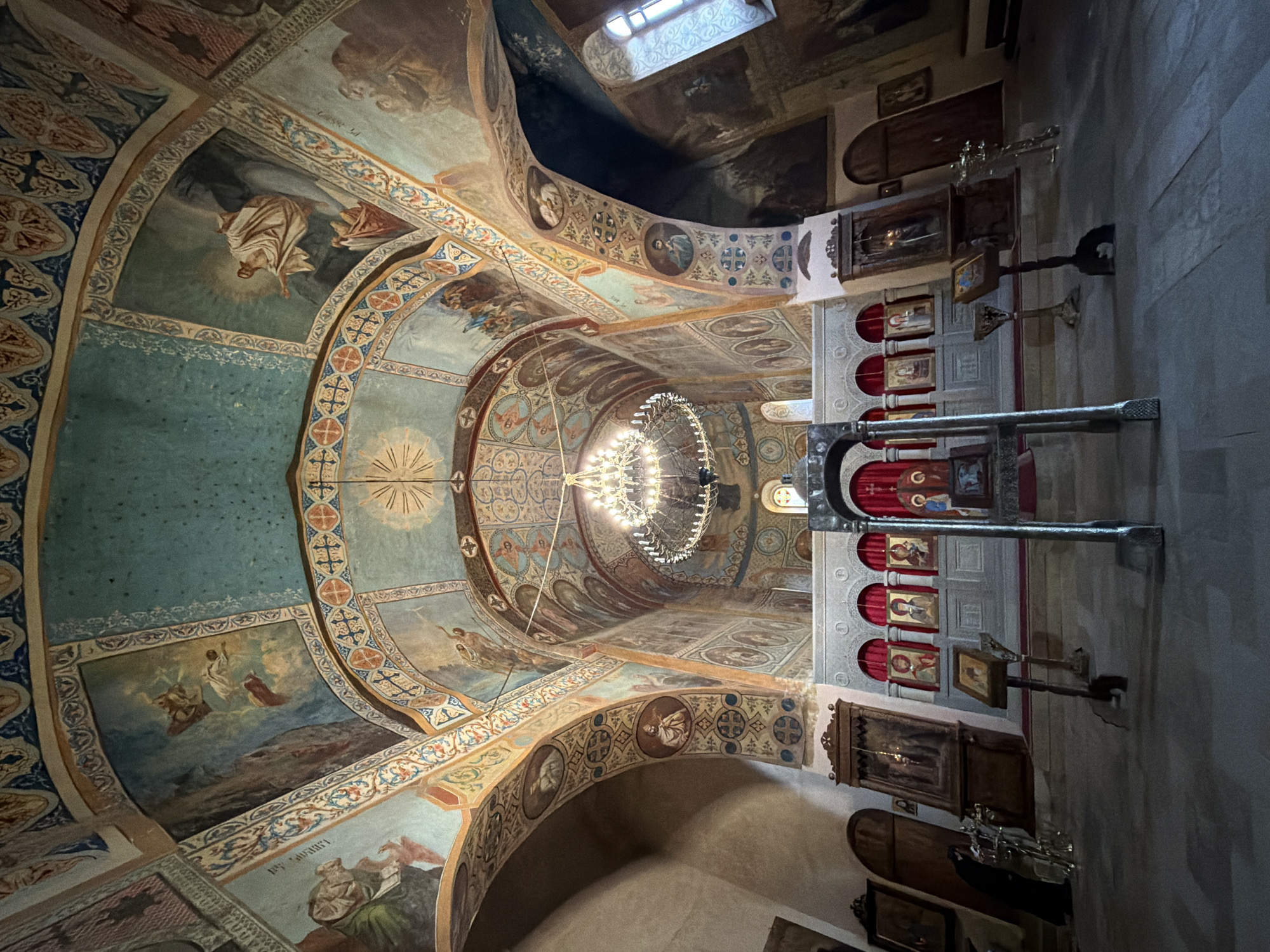 Ornate church interior with painted vaulted ceiling and chandelier