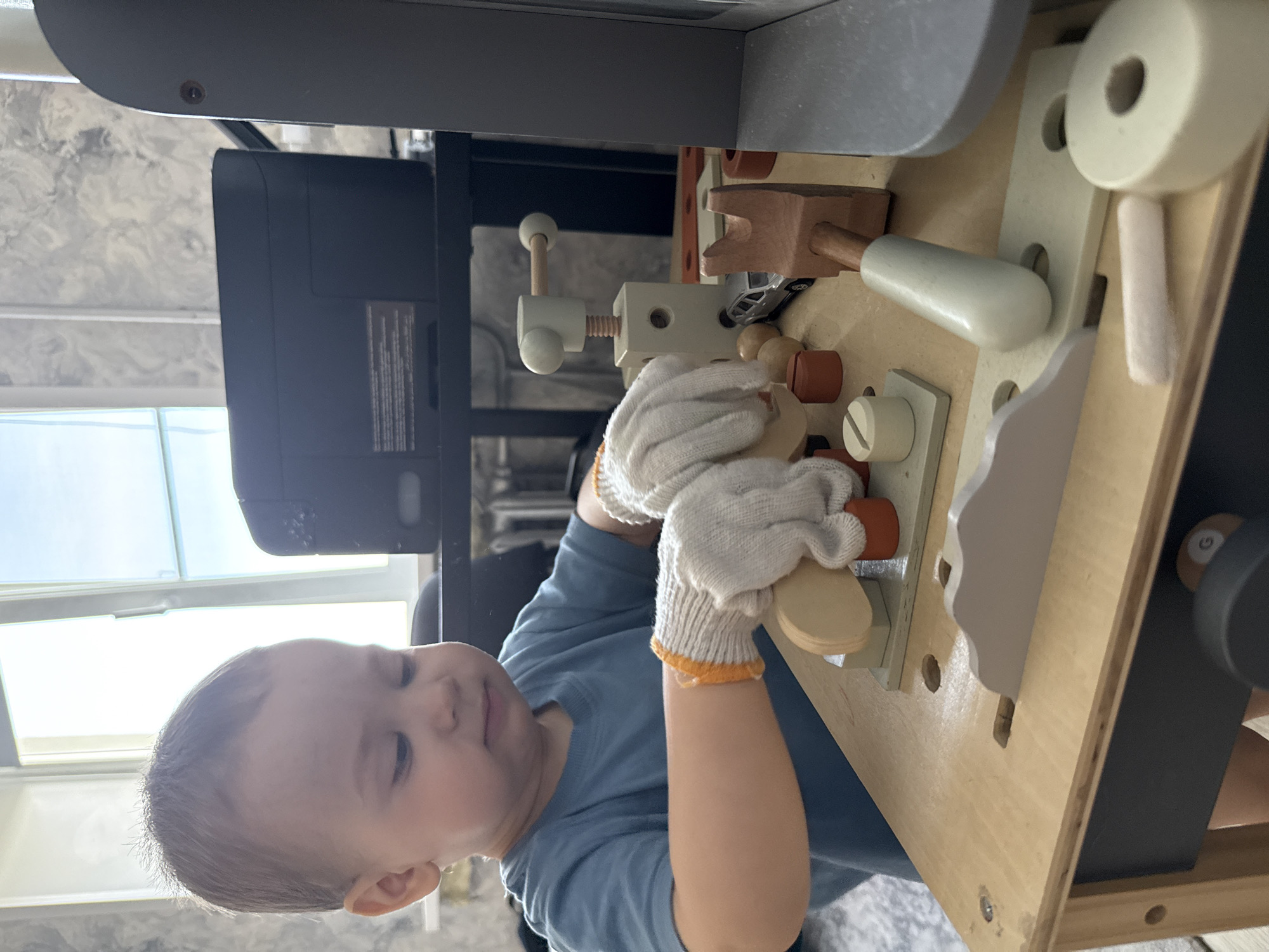 Child plays with wooden toy workbench in Rusanovo