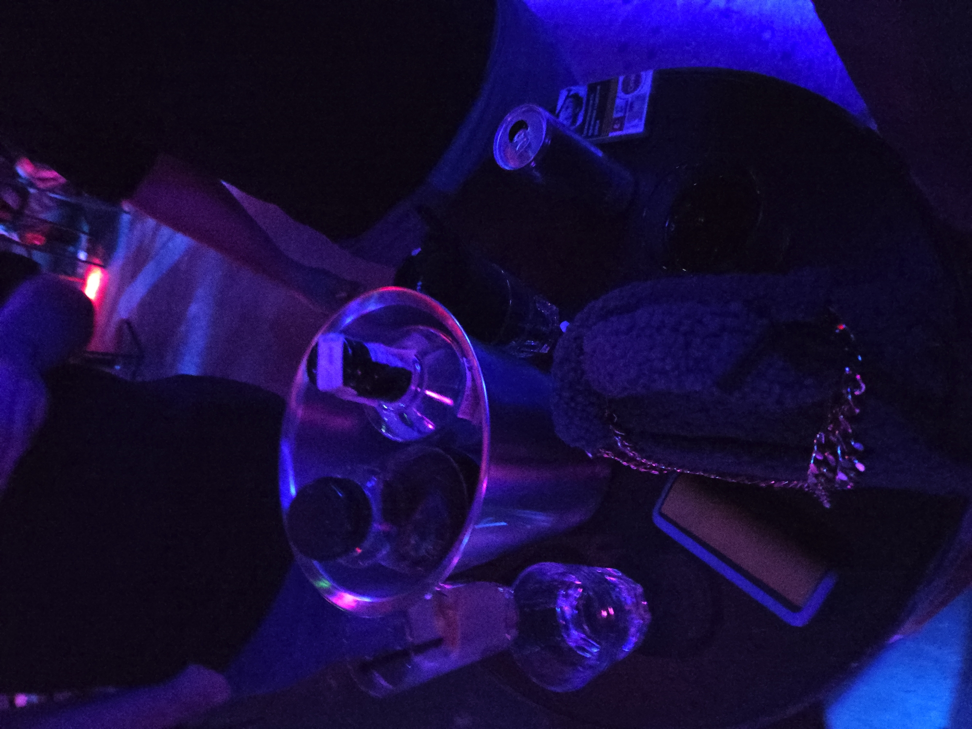 Dimly lit table with glasses and beverage documented
