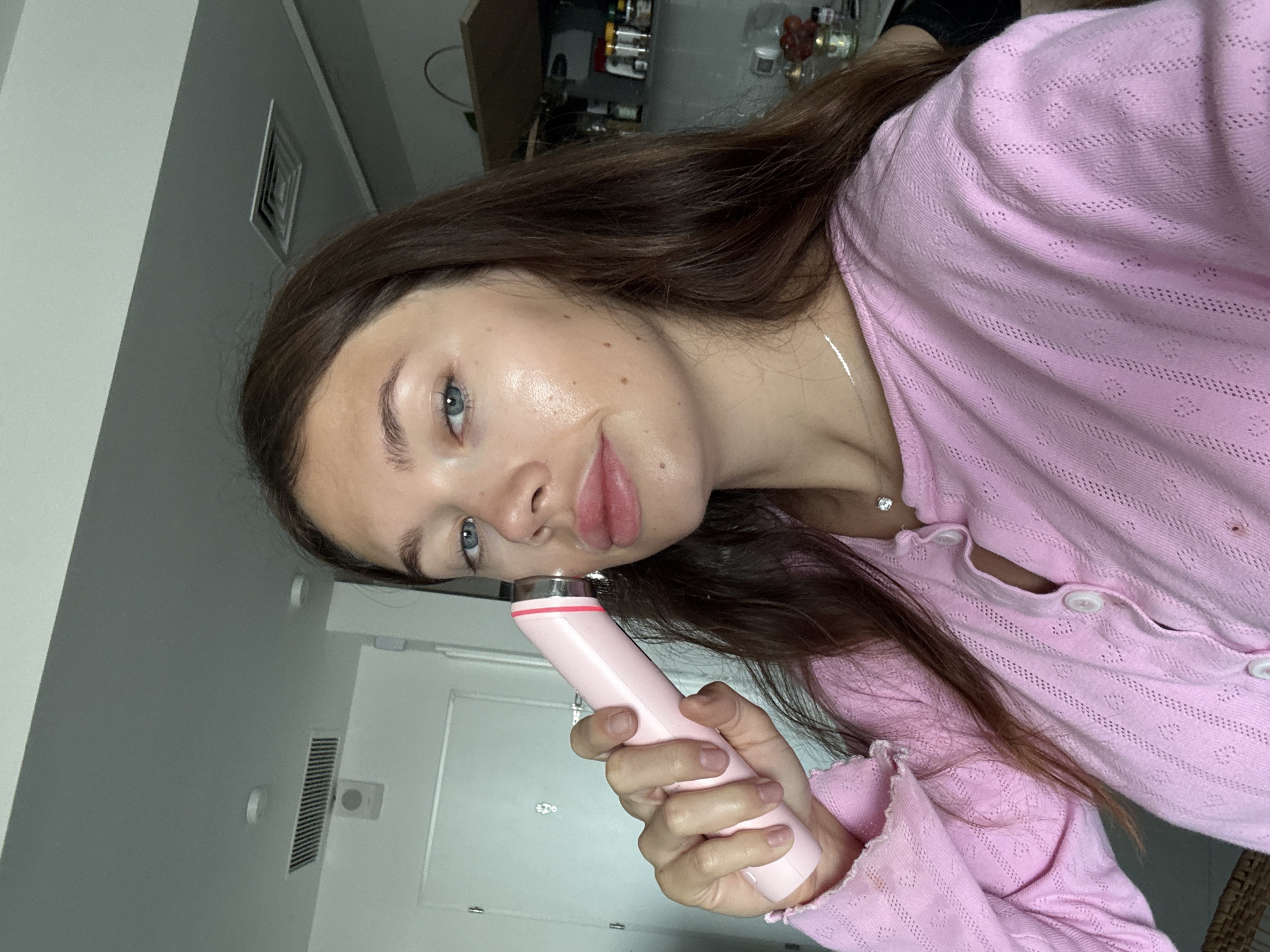 Woman uses pink facial device in Tel Aviv room