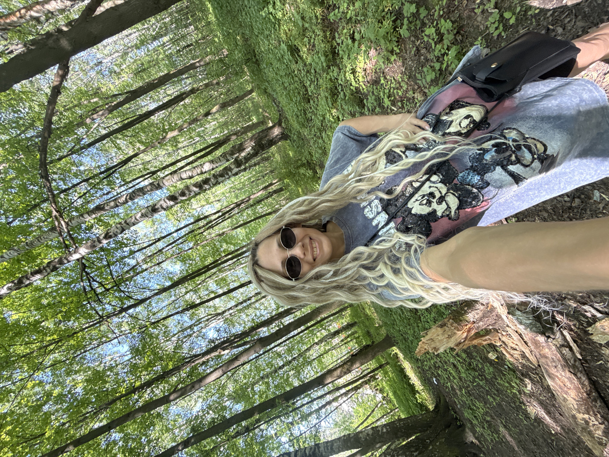 Woman rests on tree trunk in forest setting