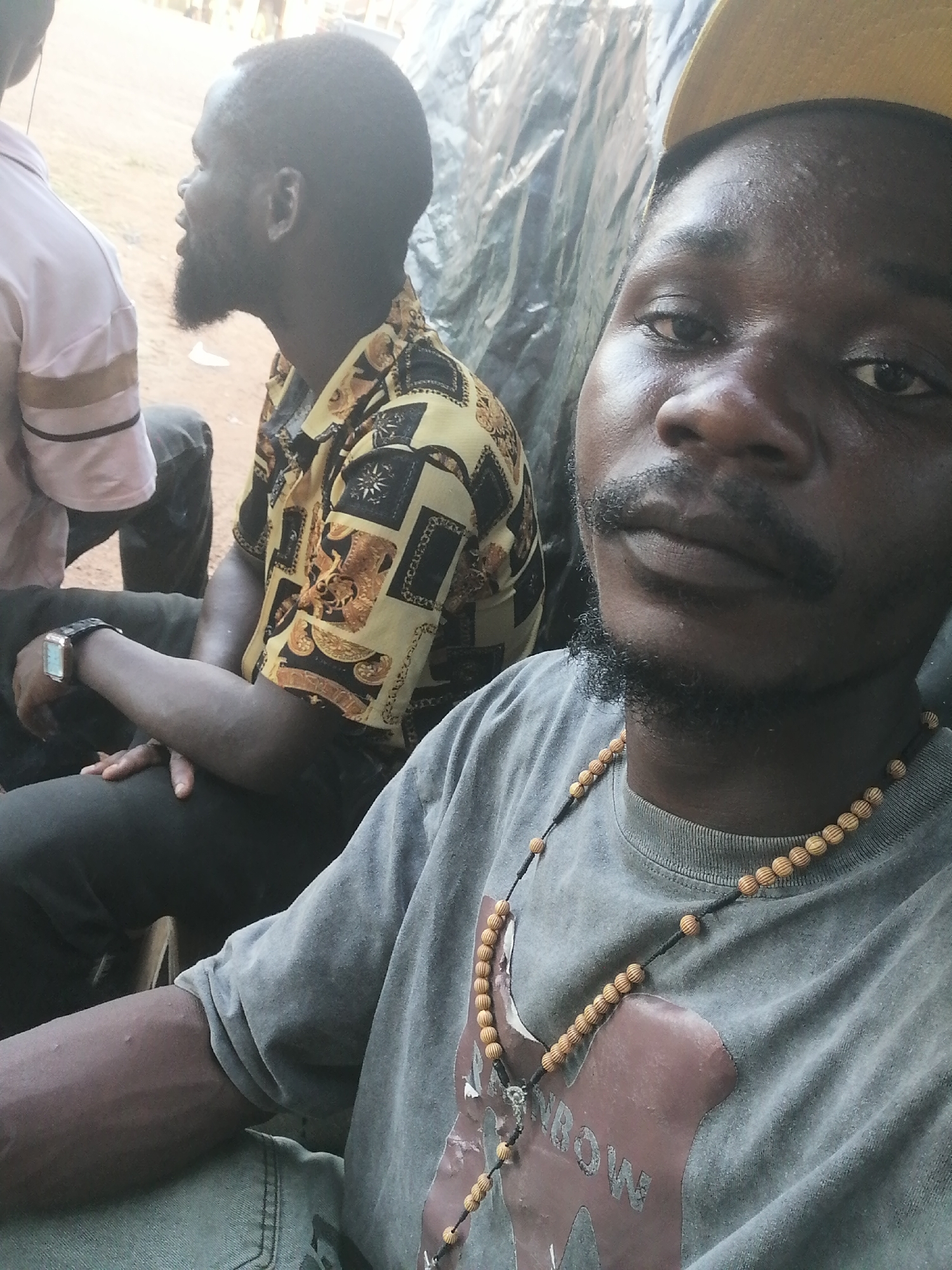 Three men gather outdoors in Jato Aka, Nigeria