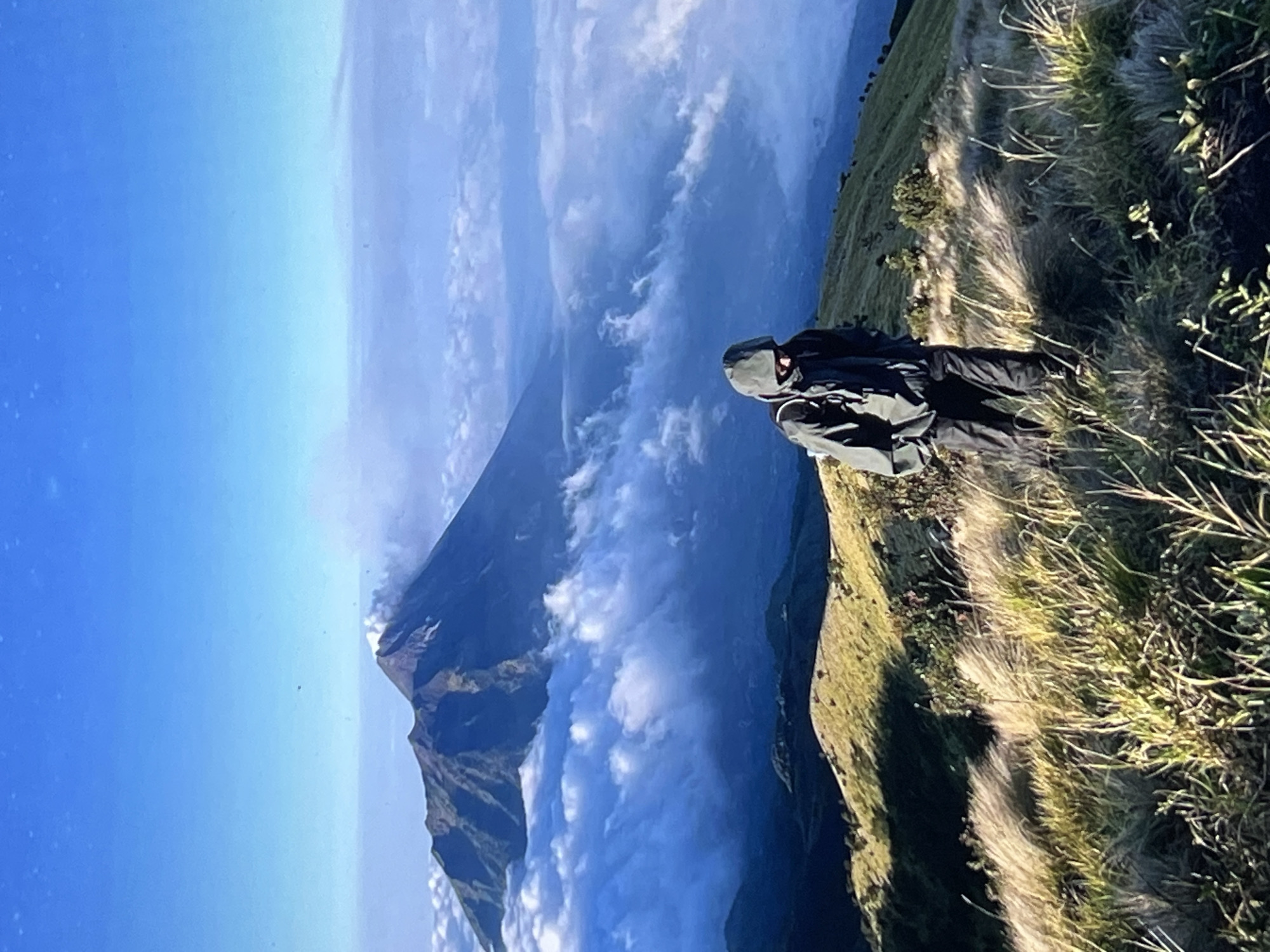 Hiker observed on mountain overlook viewing cloud-covered peaks